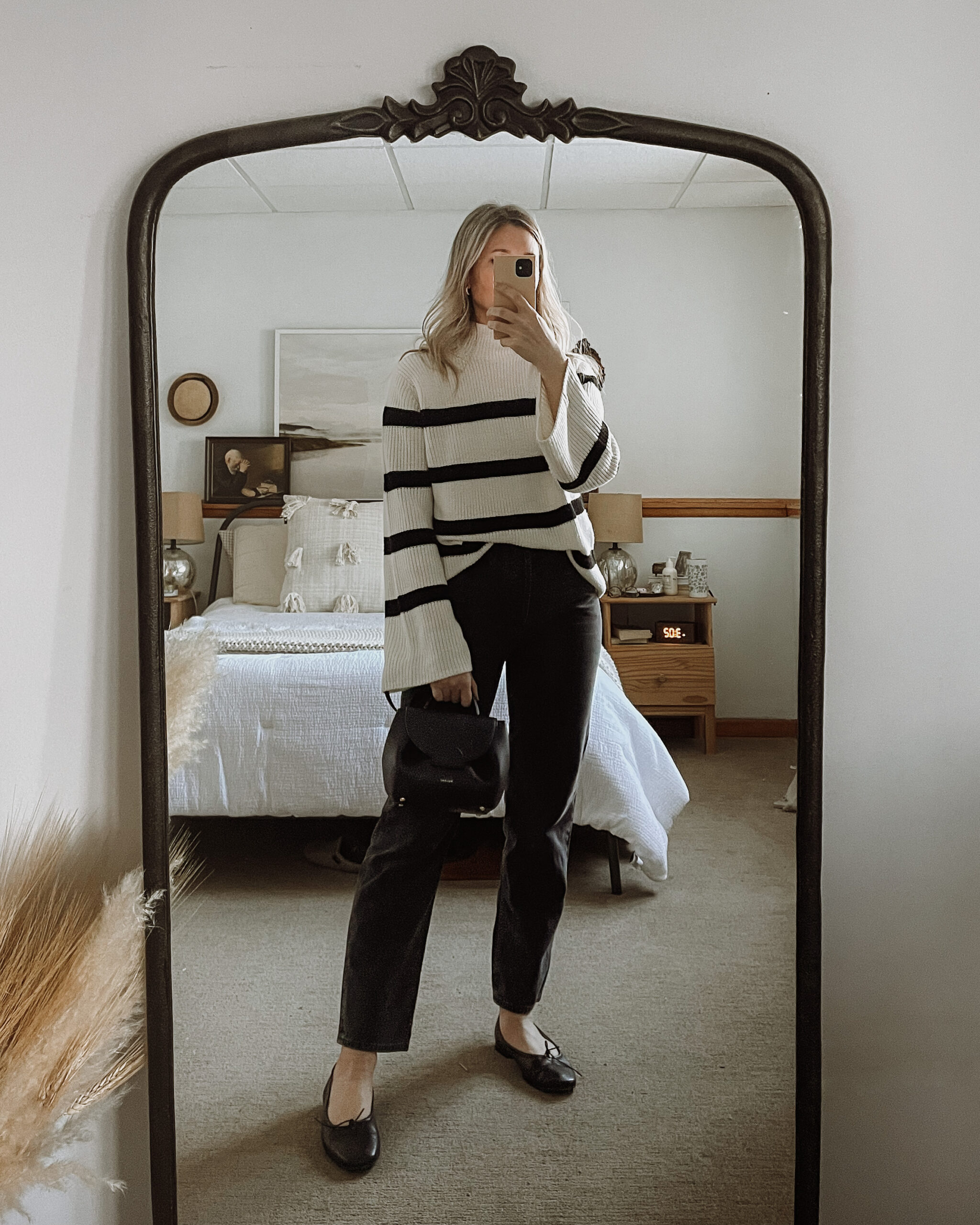 Karin Emily wears an oversized black and white striped sweater, black agolde 90's jeans, black ballet flats, and a black polene bag