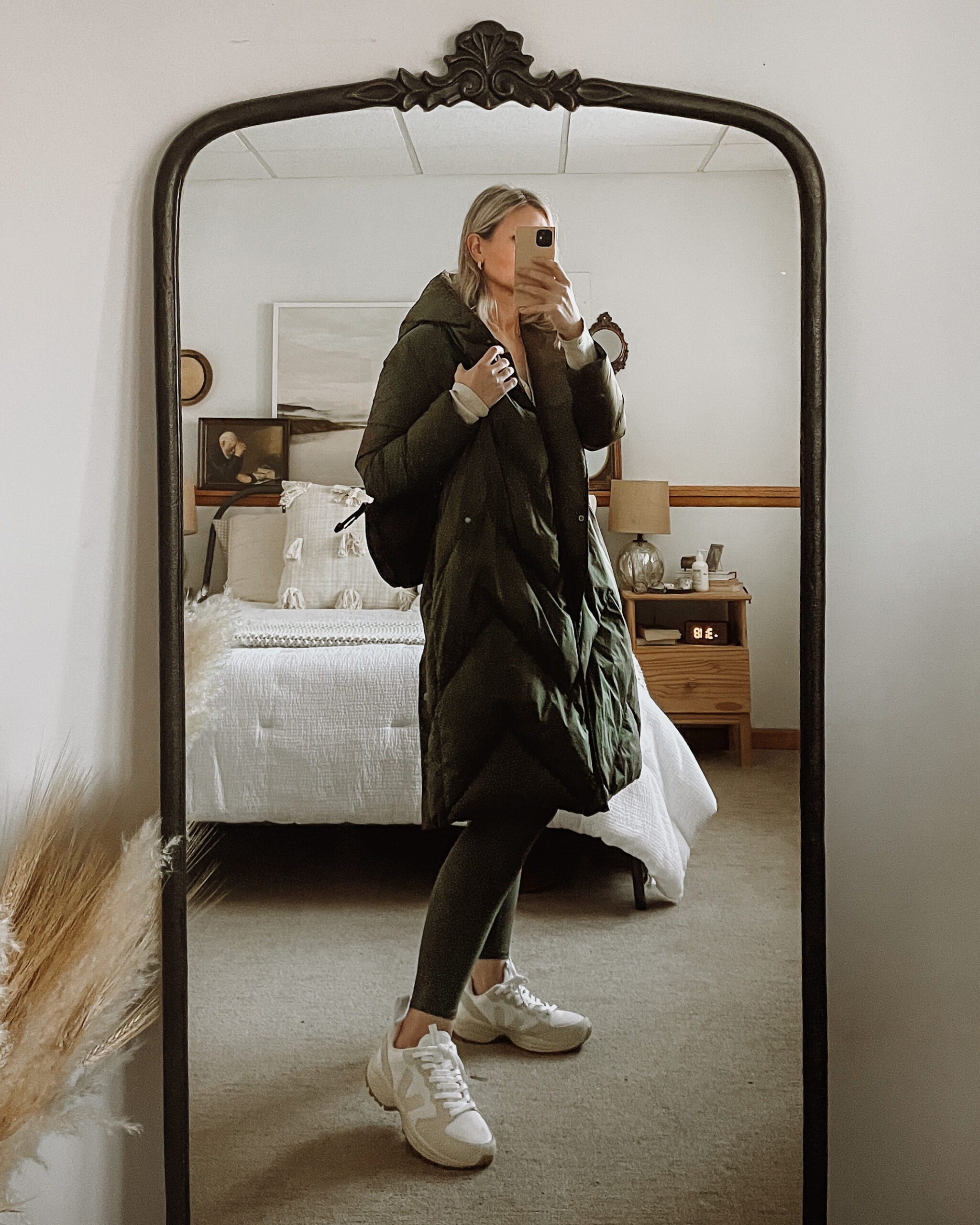 Karin Emily wears an olive green maxi puffer coat, olive green leggings from alo yoga and veja venturi sneakers