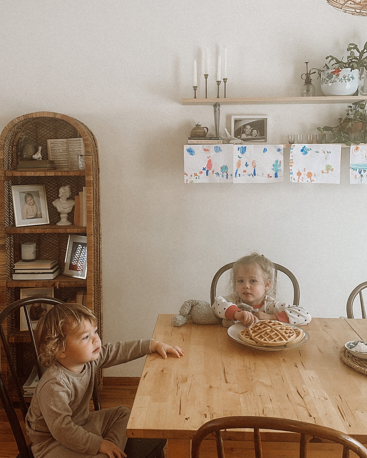 two kids sitting at a table waiting to eat waffles