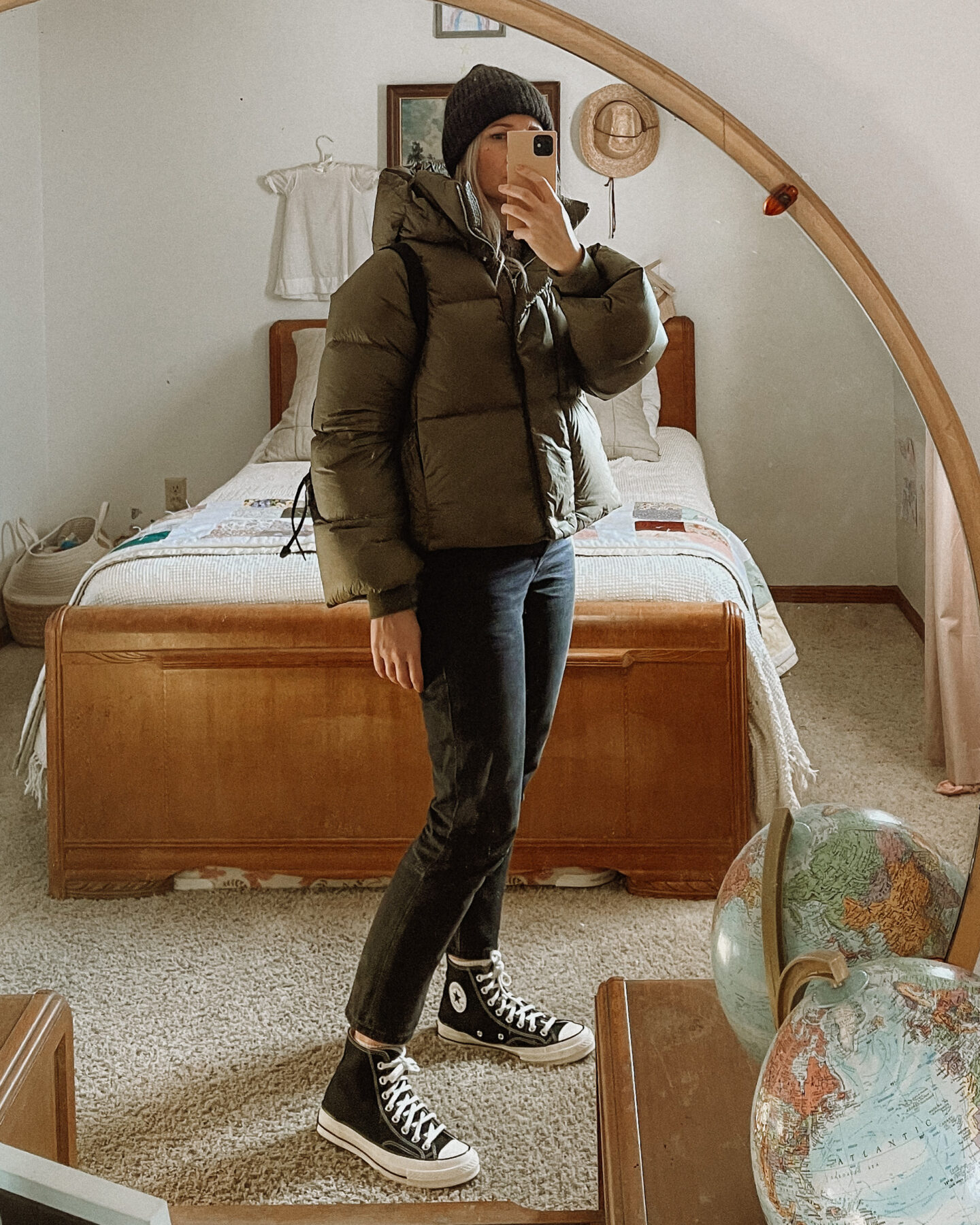 Karin Emily wears an olive green cropped puffer coat from Banana Republic, black wash everlane 90's cheeky jeans, and black high top converse sneakers