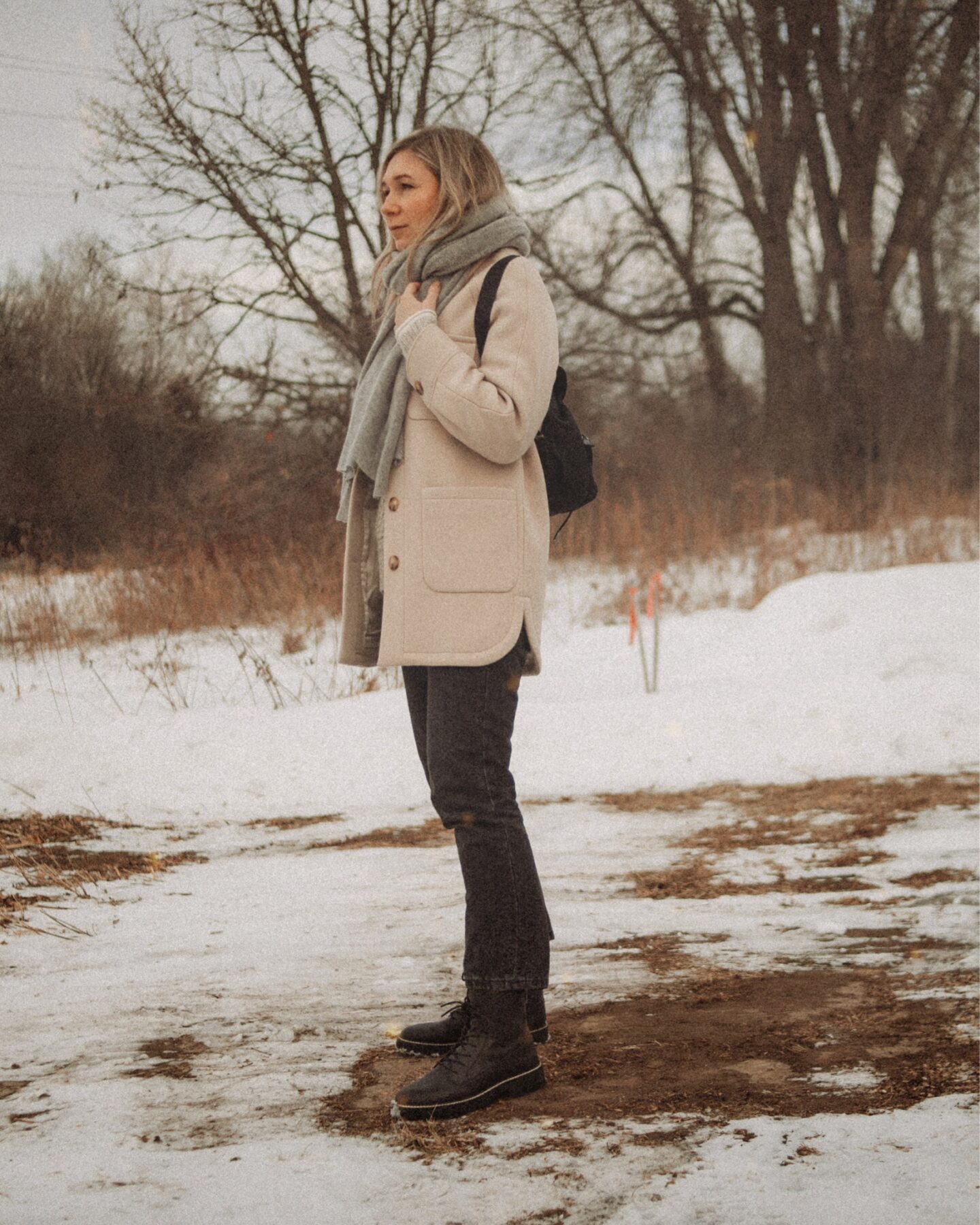 Karin Emily wears a wool shacket from Sezane, washed black 90's cheeky jeans from Everlane, and black lace up boots from Madewell