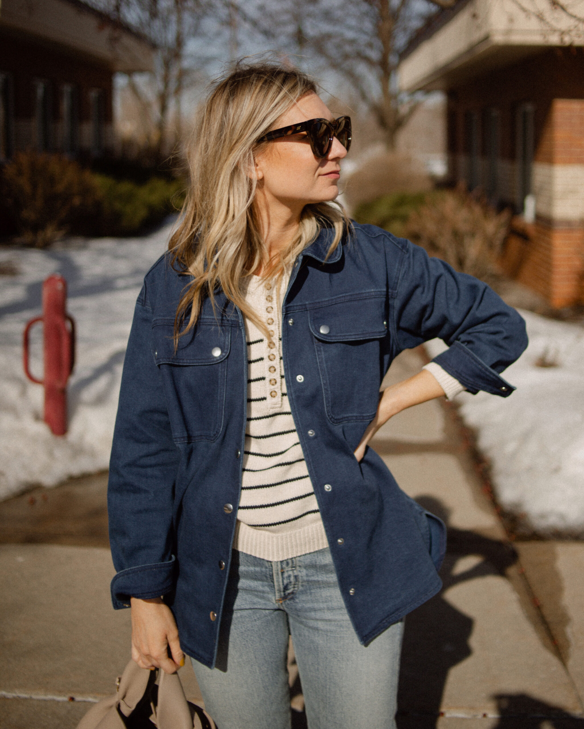 Karin Emily wears a Breton stripe sweater under a denim shirt jacket and a pair of light wash jeans