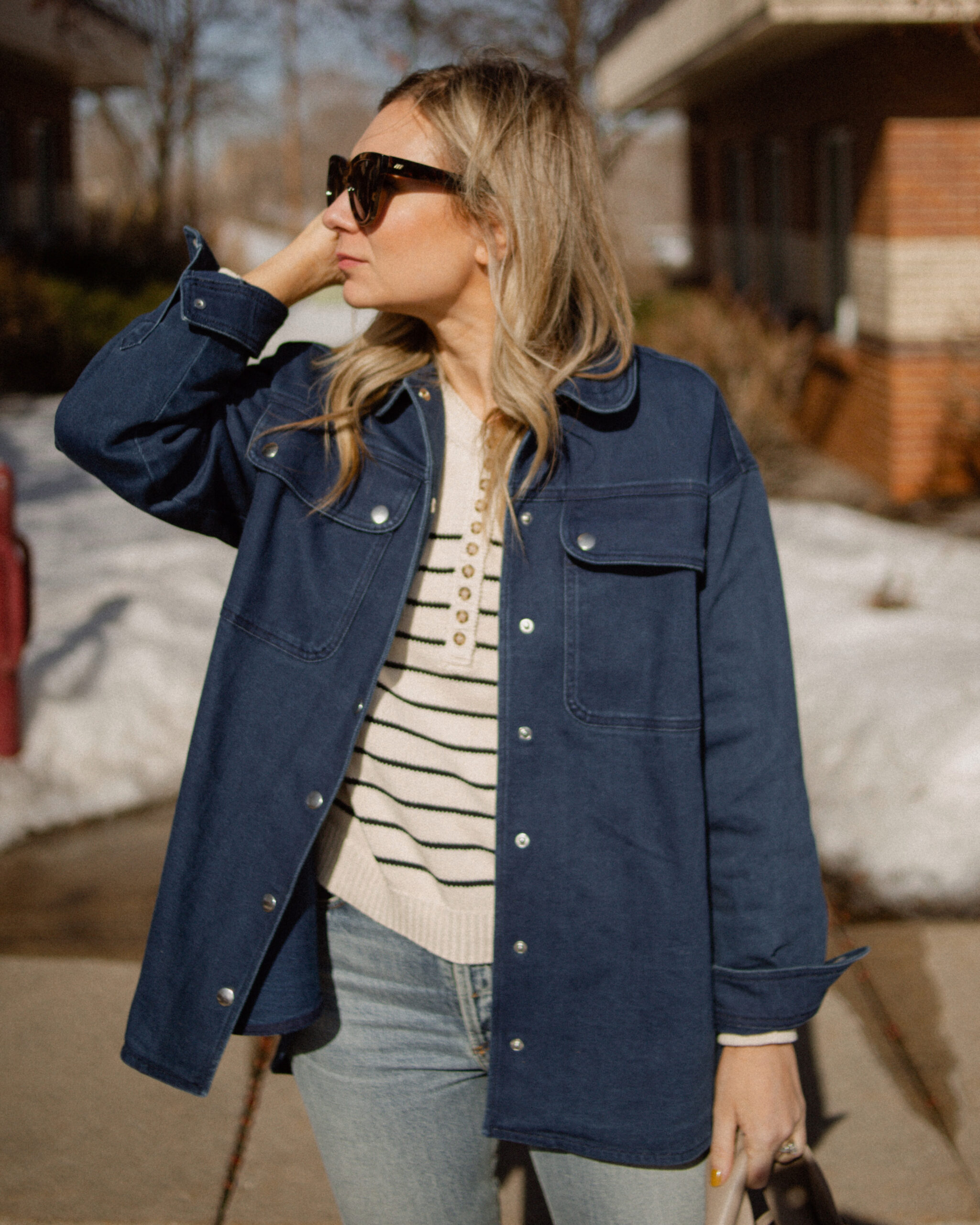 Karin Emily wears a Breton stripe sweater under a denim shirt jacket and a pair of light wash jeans