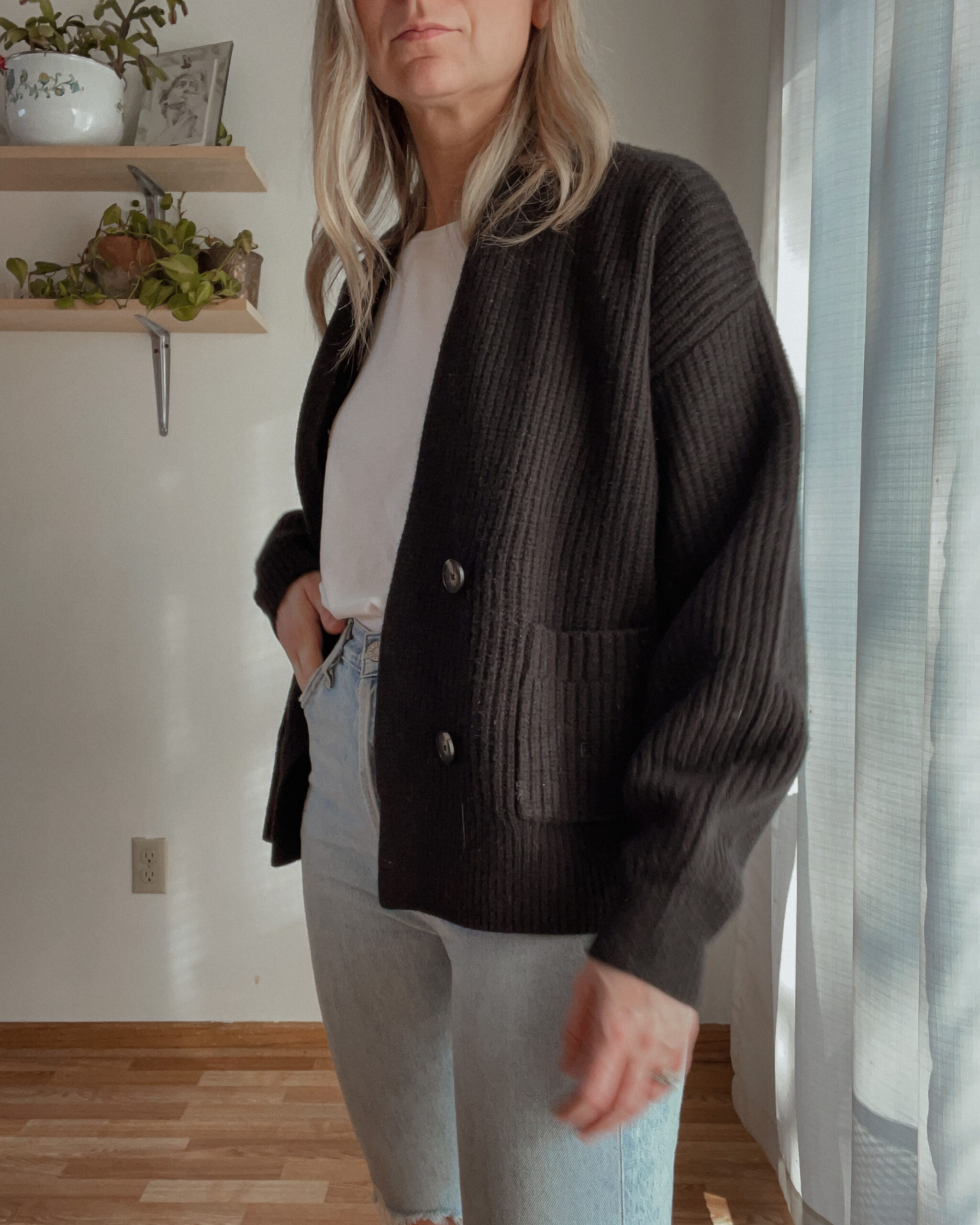 Karin EMily wears a cardigan, white tee, and agolde riley jeans