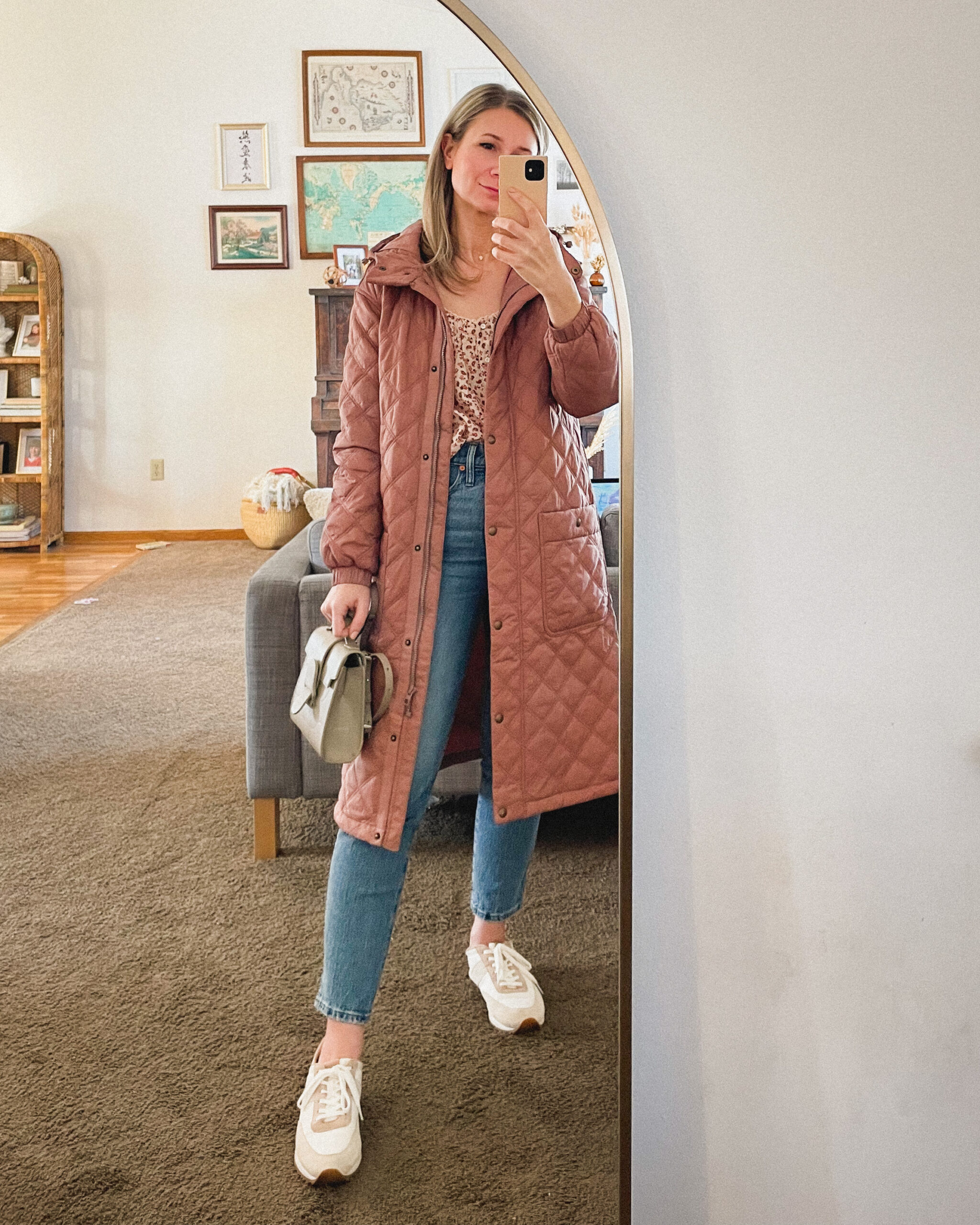 Karin Emily wears a pink quilted coat, pink floral top from Doen, Madewell perfect vintage jeans, and pink sneakers