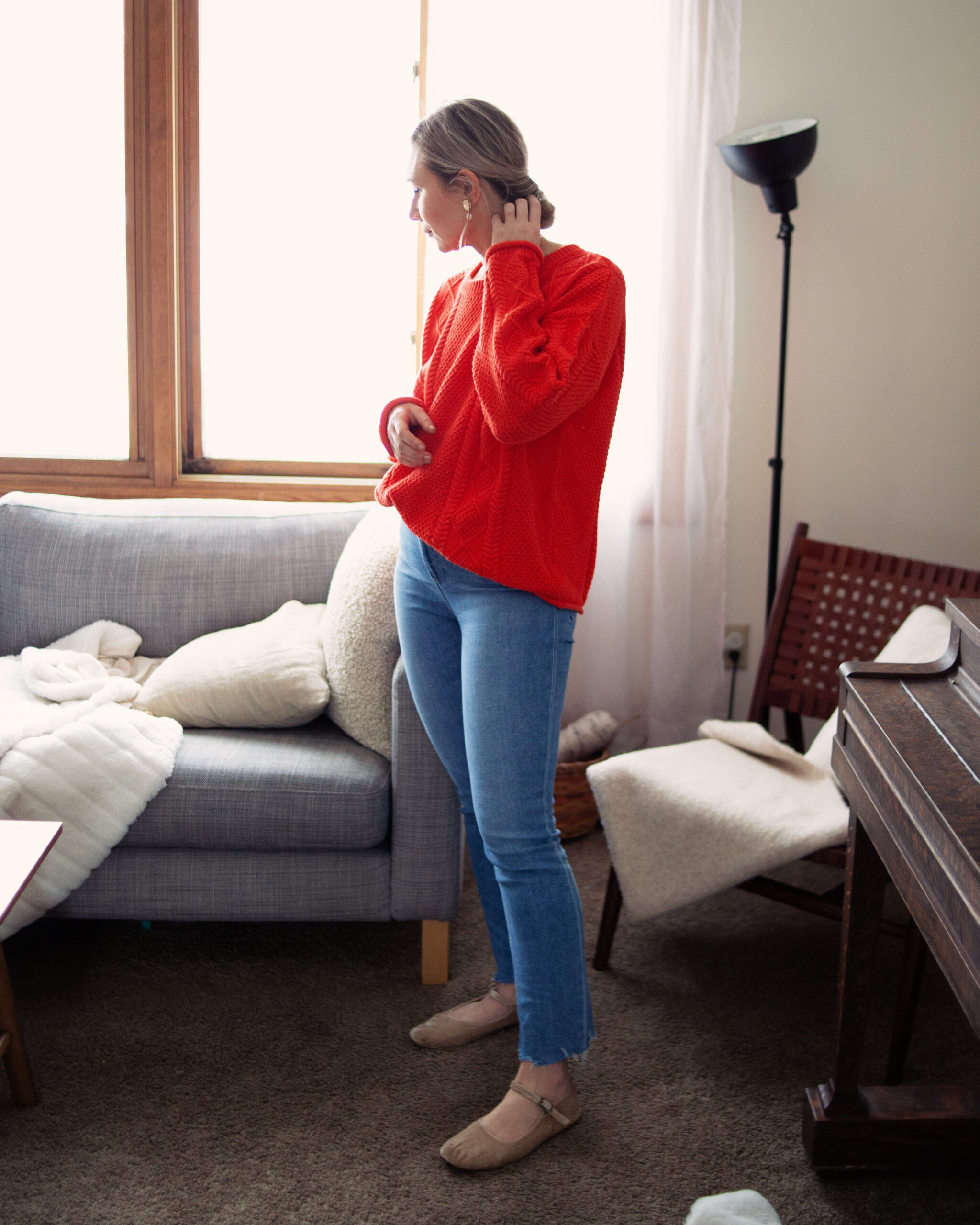 Karin Emily wears a Valentines Day outfit with a red cable knit sweater, comfy straight leg jeans, and velvet Mary Jane flats