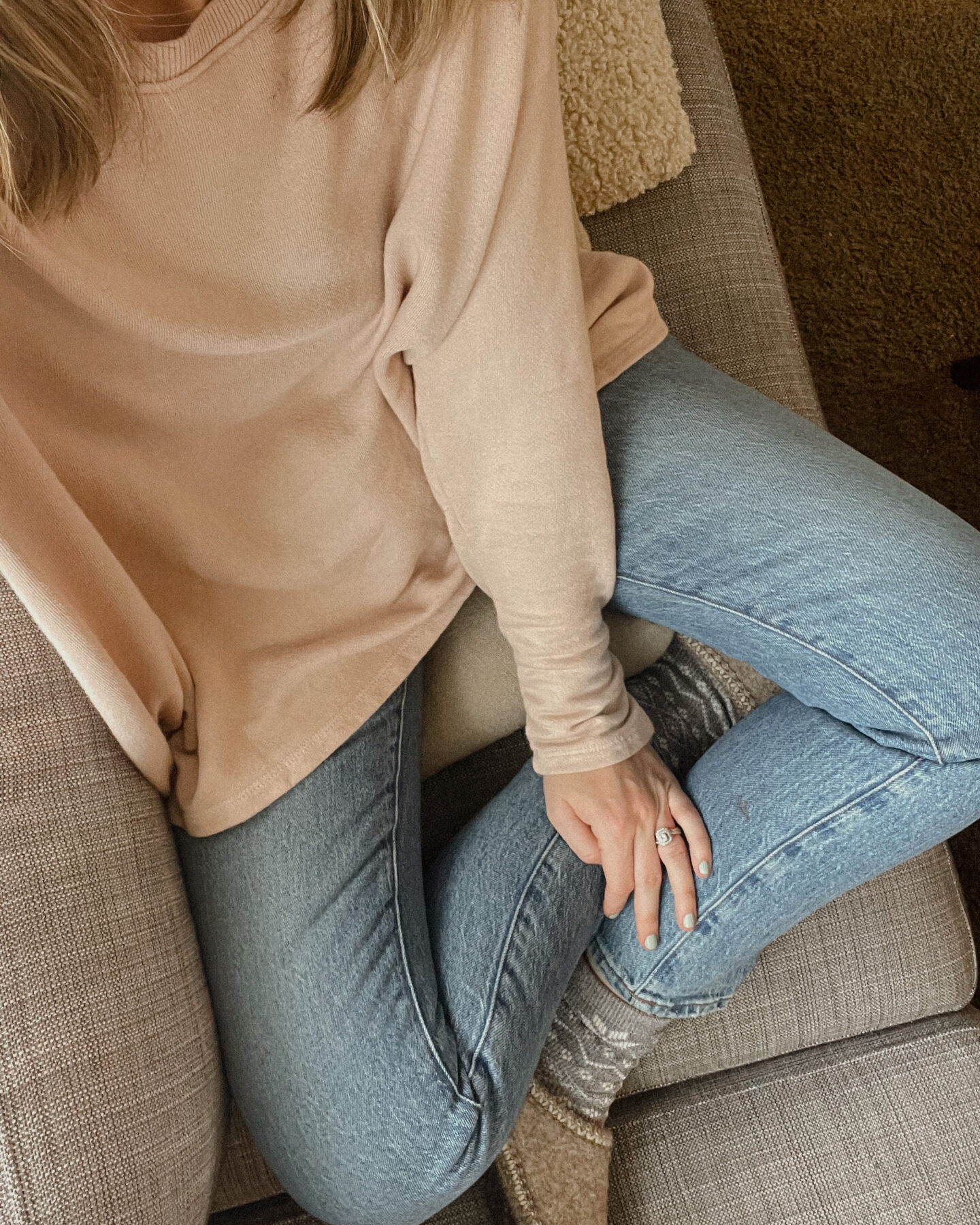 Karin Emily is wearing a blush pink sweatshirt, madewell perfect vintage jeans, and haflinger slippers