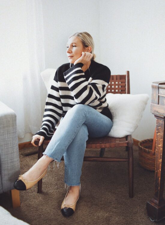Karin Emily wears a Breton stripe cashmere sweater, Agolde jeans, and Chanel inspired cap toe flats