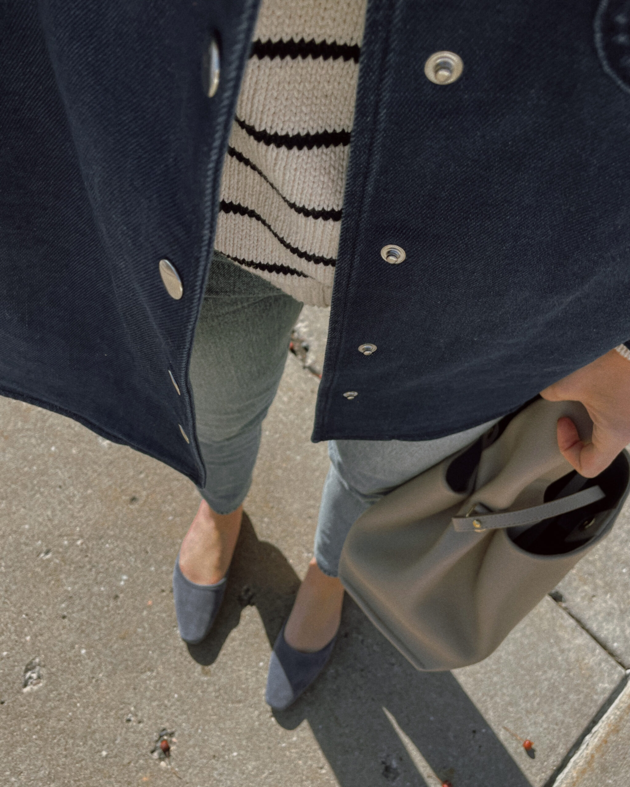 Karin Emily has an update for spring and wears a blue denim shirt jacket, breton stripe sweater, light wash jeans, and blue suede mules