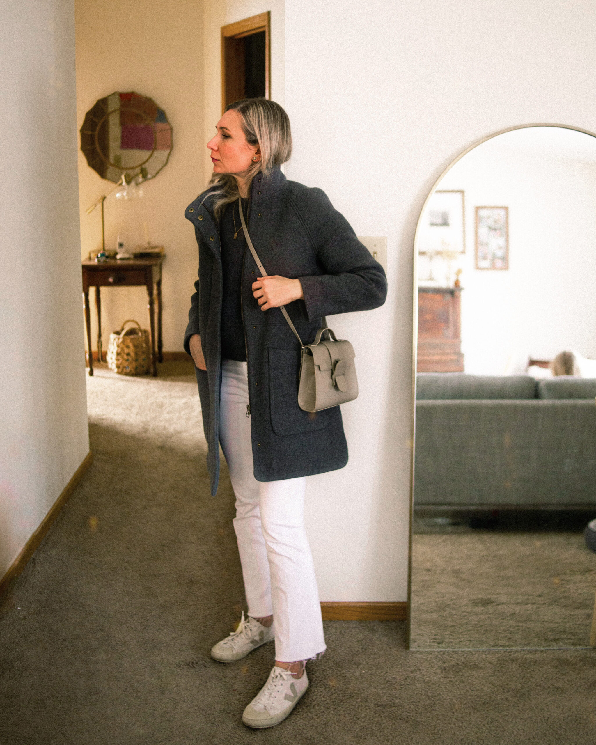 Karin Emily is dressed like the winter sky with a gray wool coat, gray wool sweater, white jeans, and veja canvas sneakers