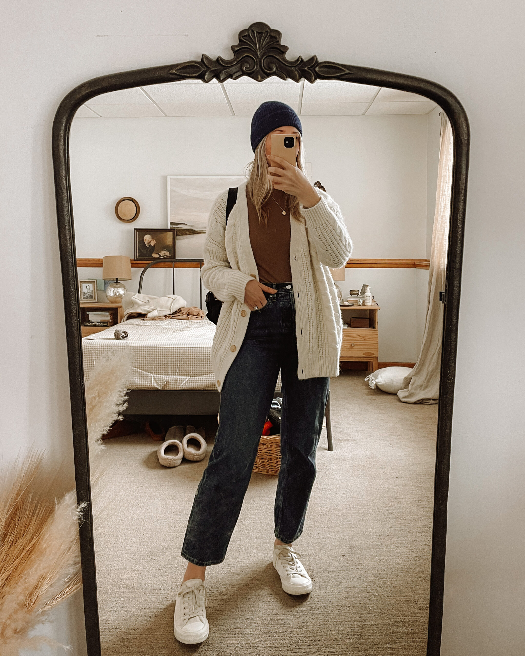 Karin Emily wears a dark wash pair of way high jeans from Everlane, a Madewell bodysuit, jenni Kayne cable knit cardigan, and converse sneakers