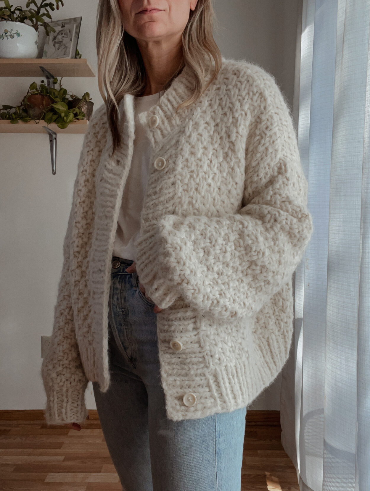 Karin EMily wears a cardigan, white tee, and agolde riley jeans