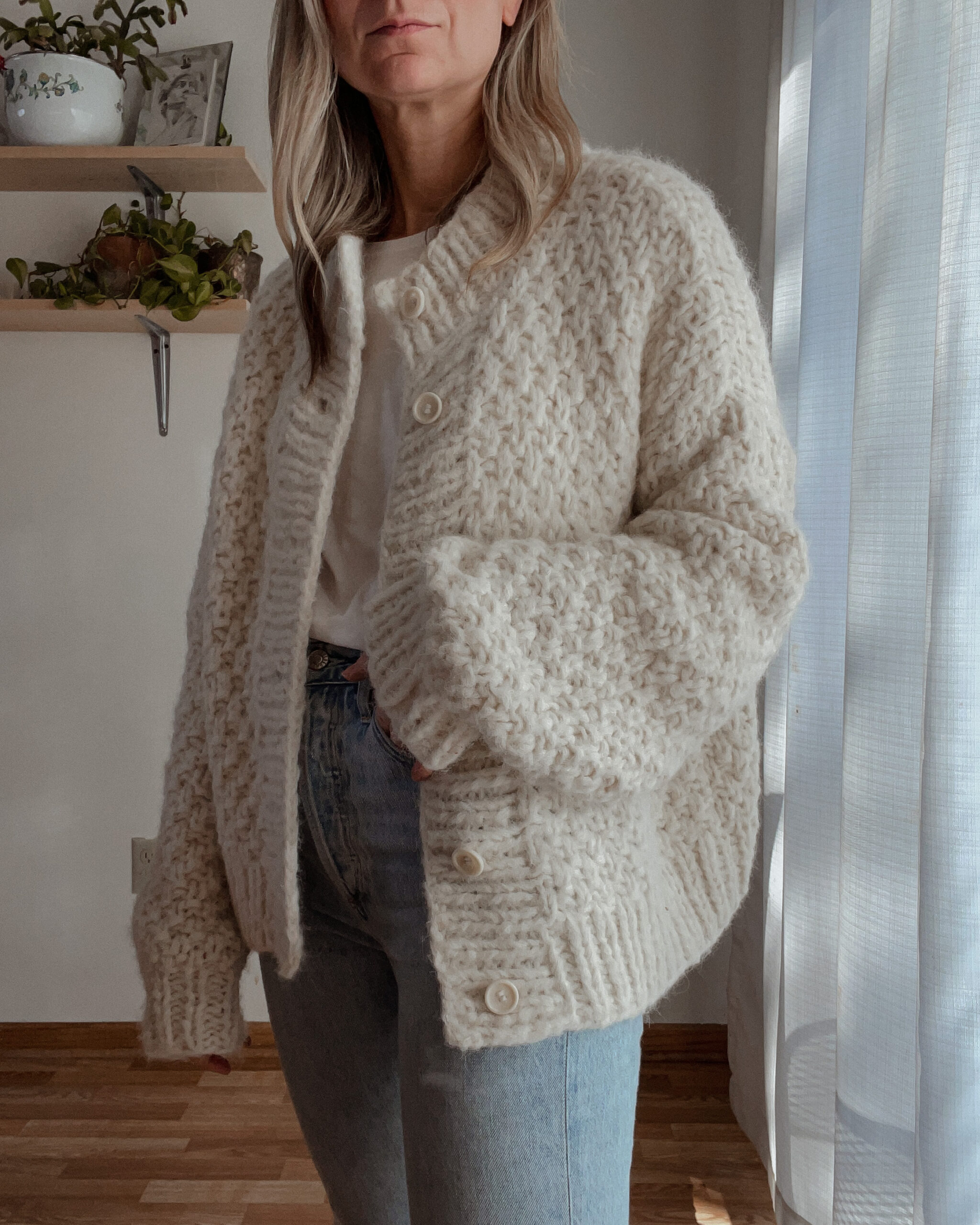 Karin EMily wears a cardigan, white tee, and agolde riley jeans