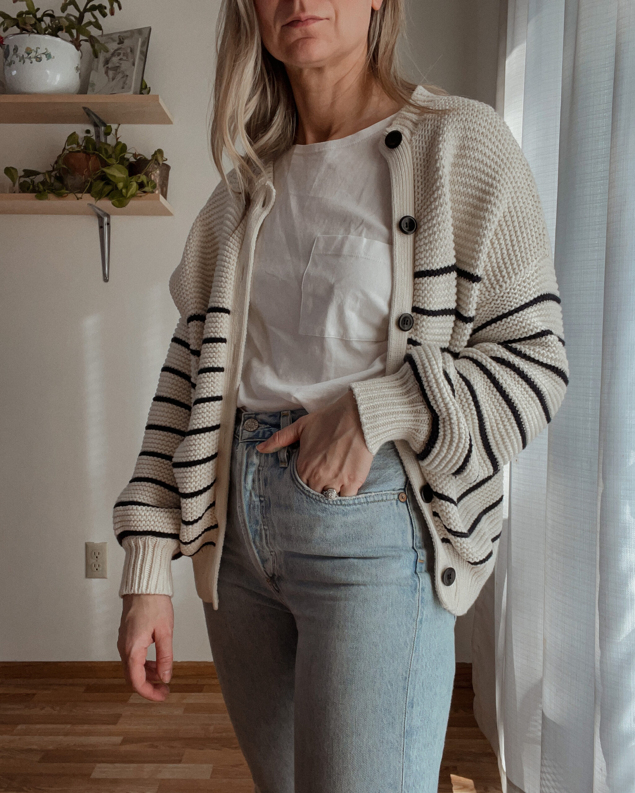 Karin EMily wears a cardigan, white tee, and agolde riley jeans