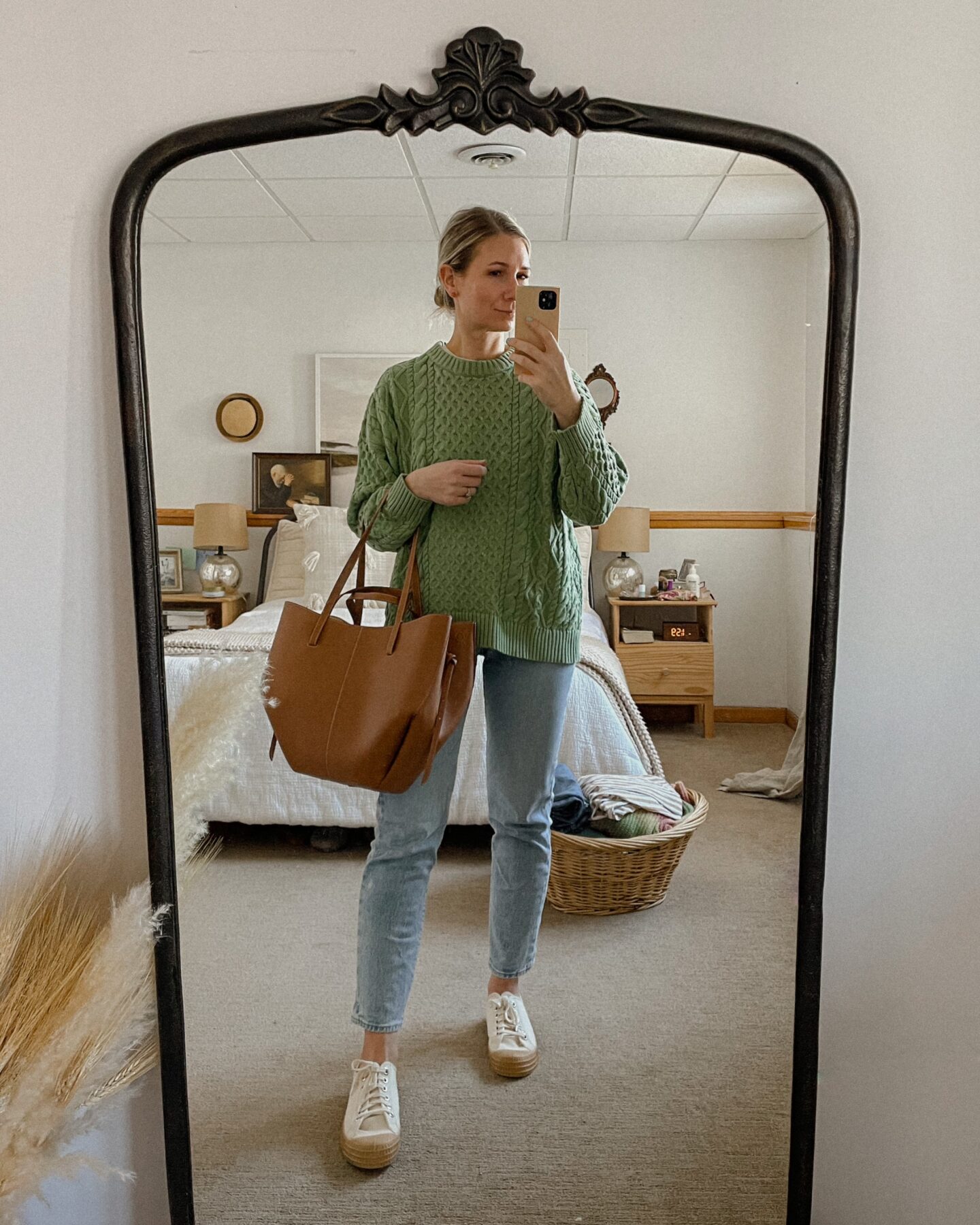 Karin Rambo wears a shamrock green sweater from demylee, levi's wedgie icon jeans, canvas sneakers, and a polene tote bag