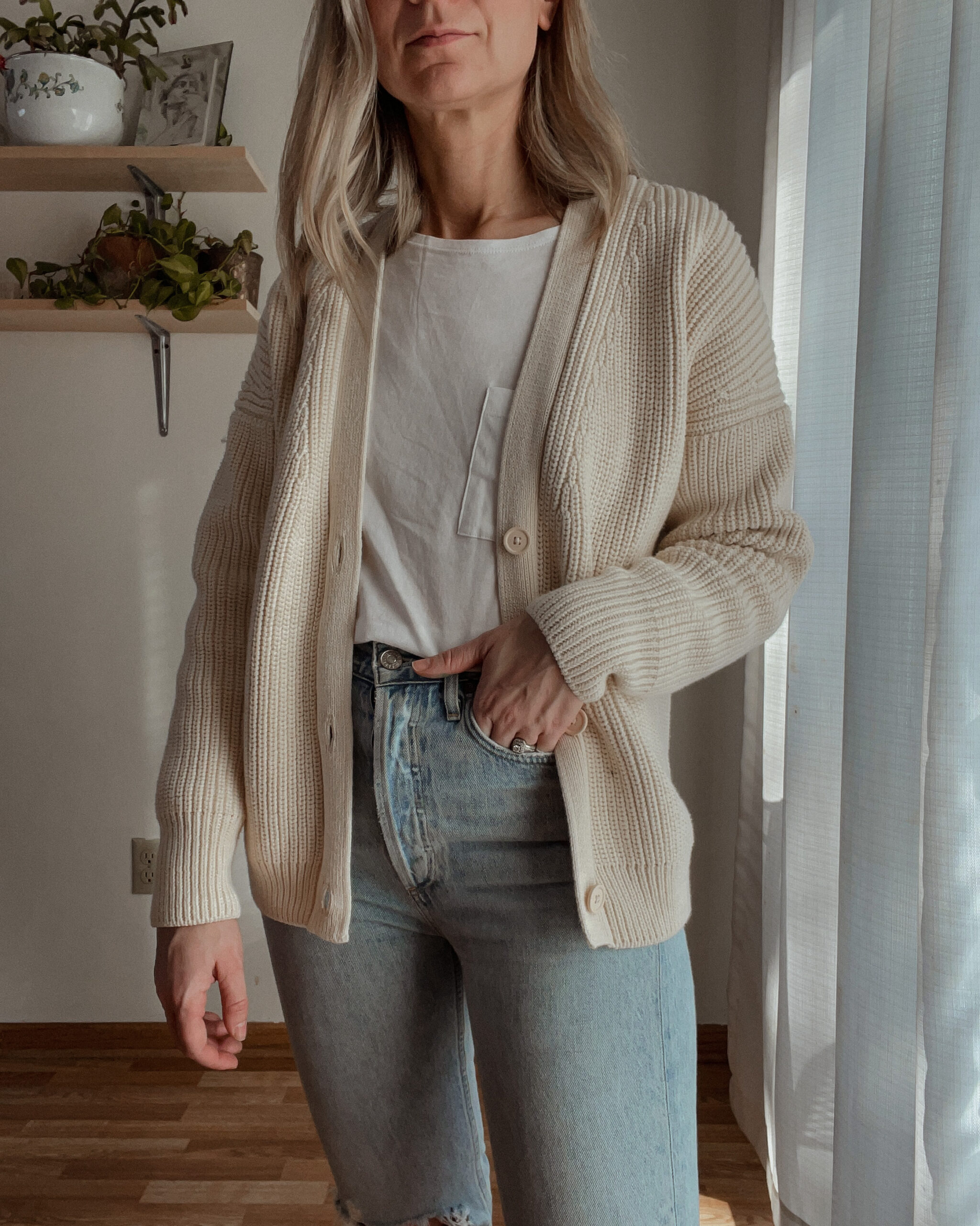 Karin EMily wears a cardigan, white tee, and agolde riley jeans