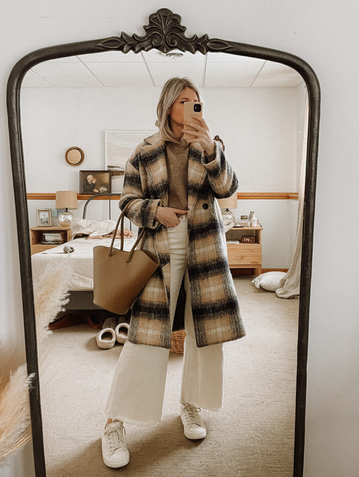 Karin Emily wears a plaid coat from Madewell, a hooded sweater from Sezane, and wide leg jeans from AYR