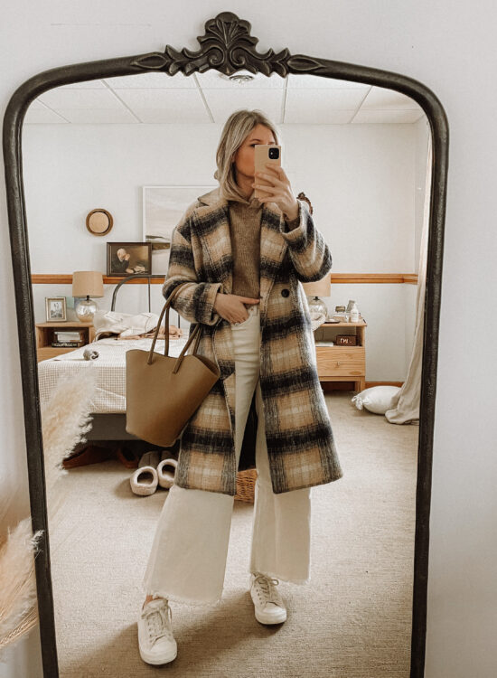 Karin Emily wears a plaid coat from Madewell, a hooded sweater from Sezane, and wide leg jeans from AYR