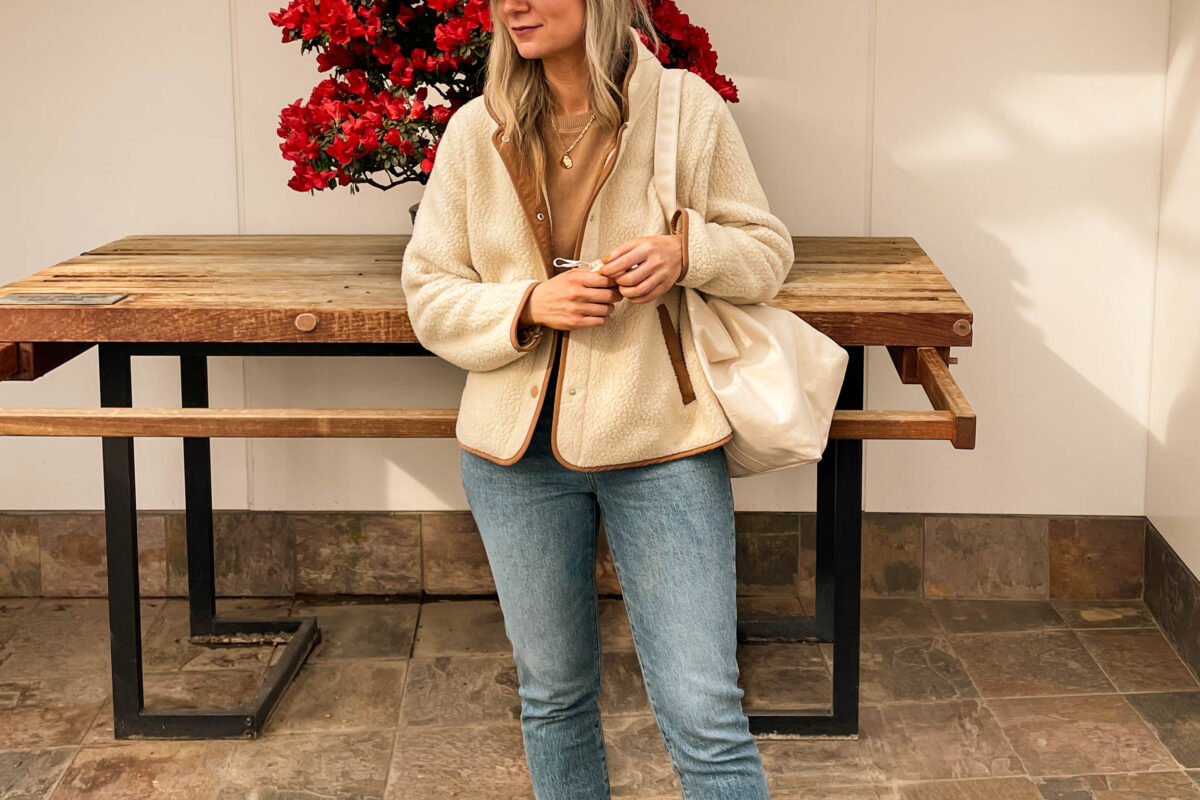 Karin Emily is Wearing Comfort Clothes with a pair of Madewell Perfect Vintage Jeans, J. Crew Cream Fleece Jacket, It is Well L.A. Camel colored sweater, and canvas sneakers