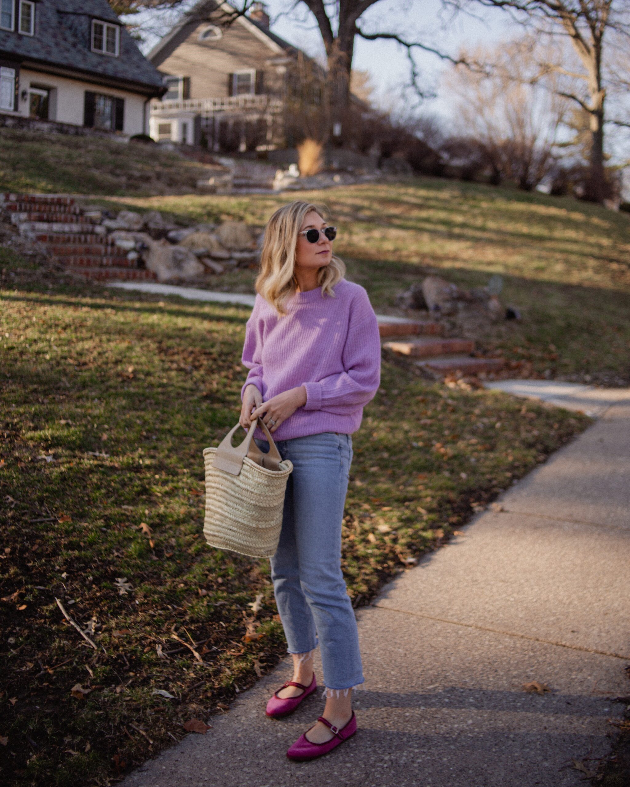 Karin Emily wears a purple sweater with light wash re/done jeans, and pink mary jane flats