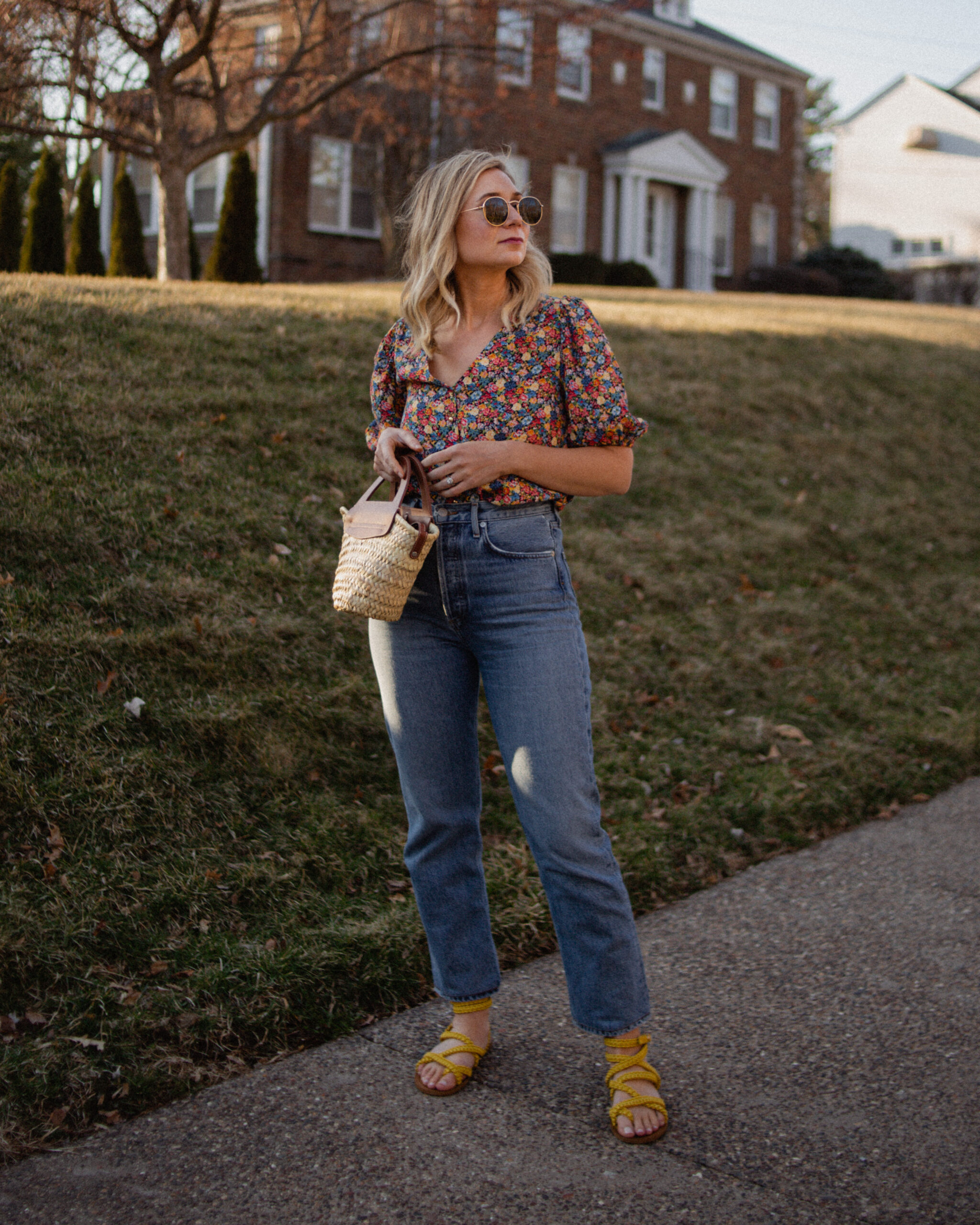 Karin Emily wears a floral top and yellow sandals from Sezane paired with a straight leg pair of jeans from Agolde