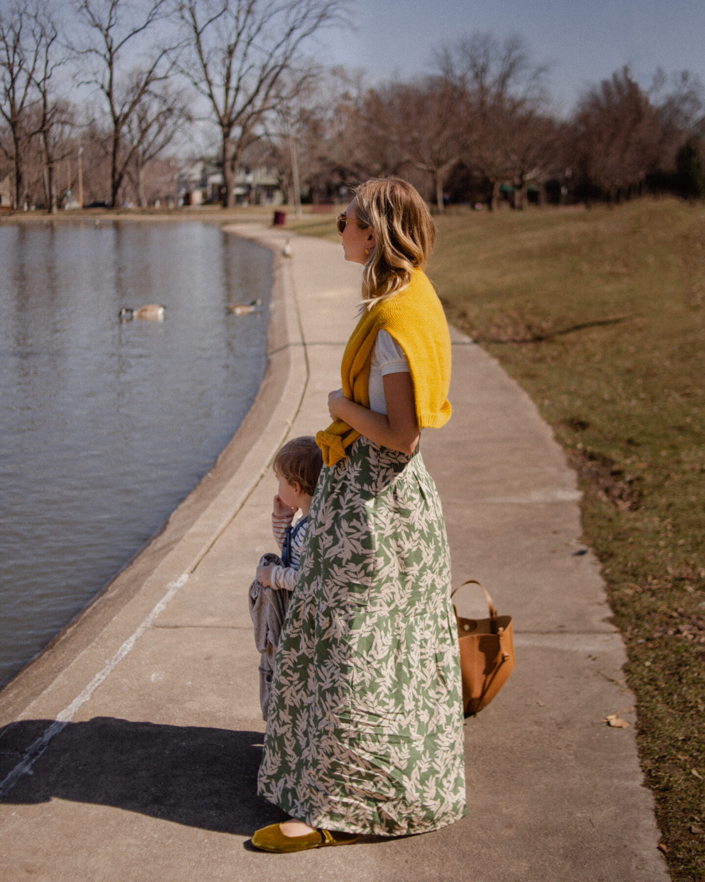 Karin Emily wears a floral maxi skirt, yellow sweater, puff sleeve tee, and green mary jane flats