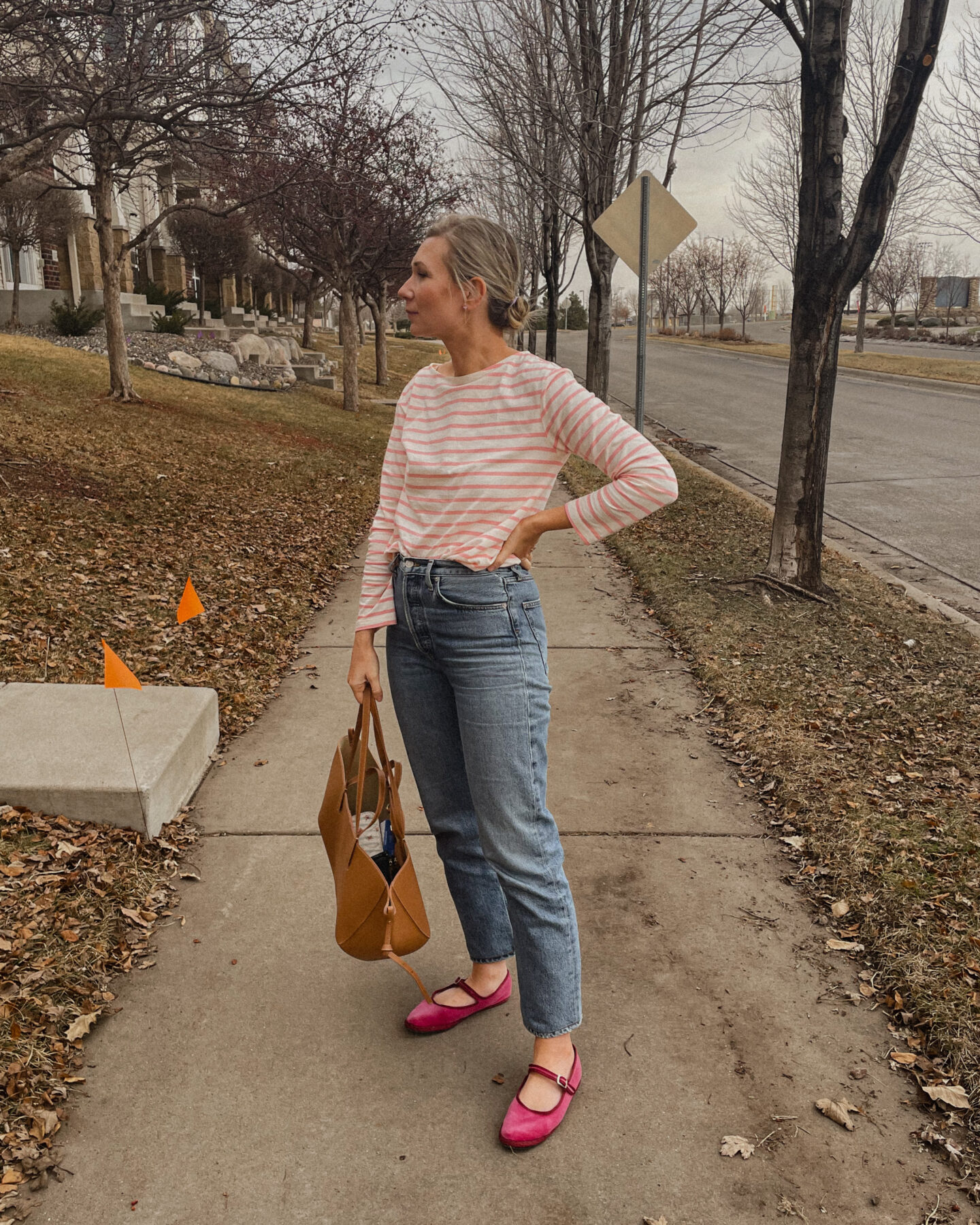 Karin Emily wear a pink stripe shirt with agold straight leg jeans, and pink mary jane flats