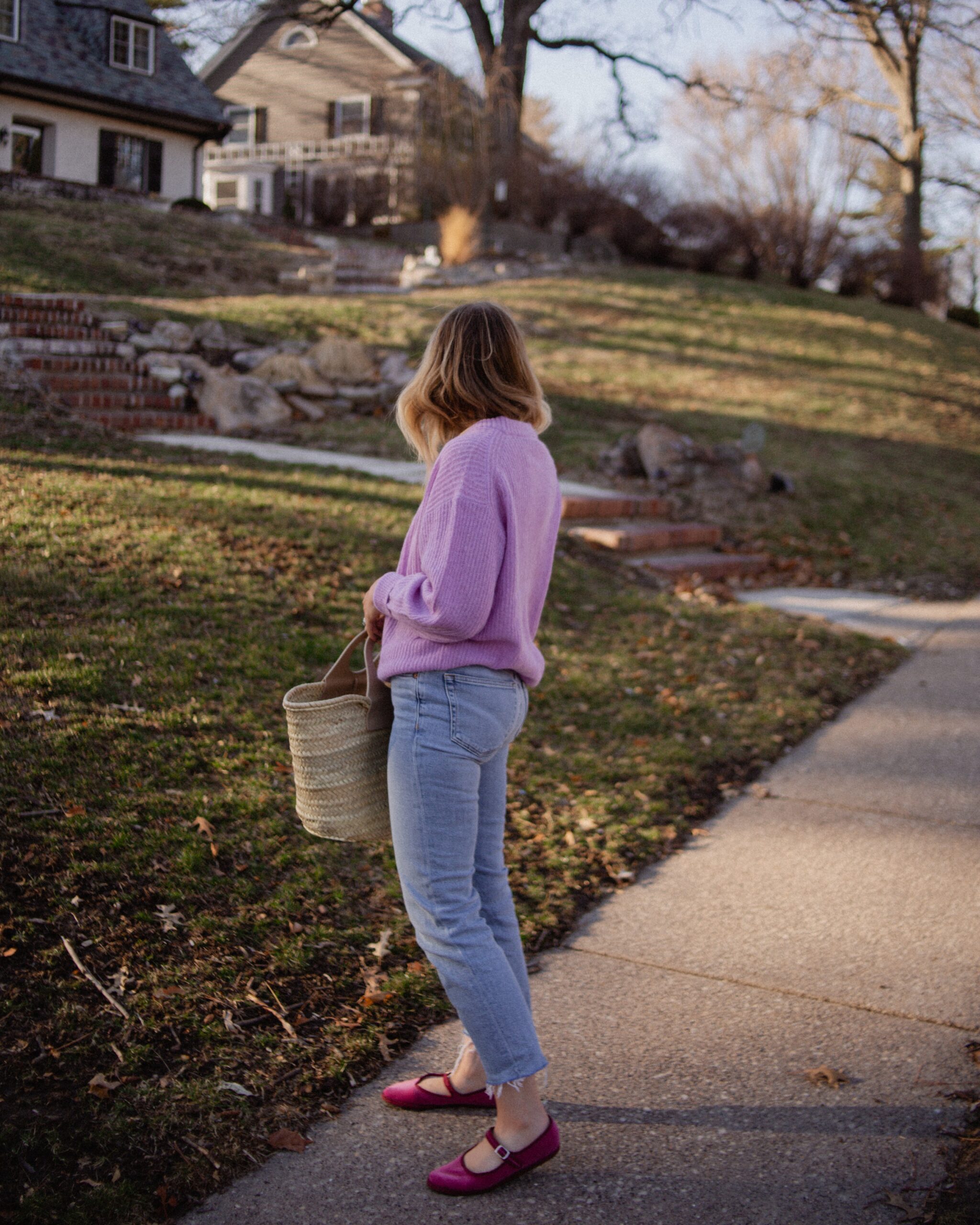 Karin Emily wears a purple sweater with light wash re/done jeans, and pink mary jane flats