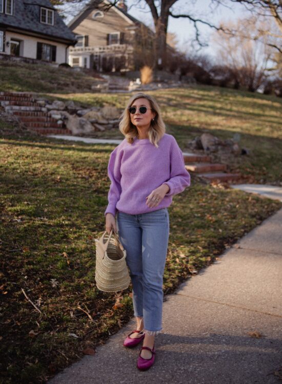 Karin Emily wears a purple sweater with light wash re/done jeans, and pink mary jane flats