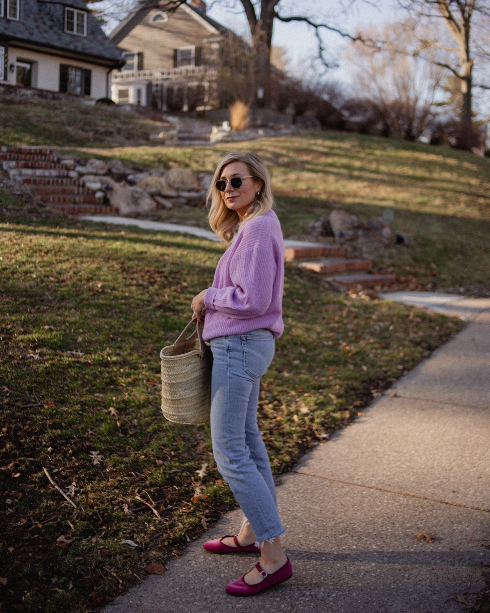 Karin Emily wears a purple sweater with light wash re/done jeans, and pink mary jane flats