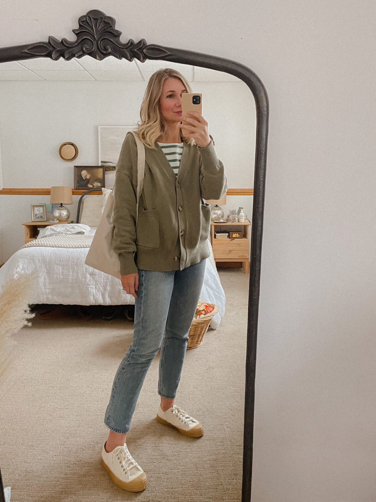 Karin Emily wears shades of green with a green cardigan, green breton striped shirt, straight leg jeans, and canvas sneakers