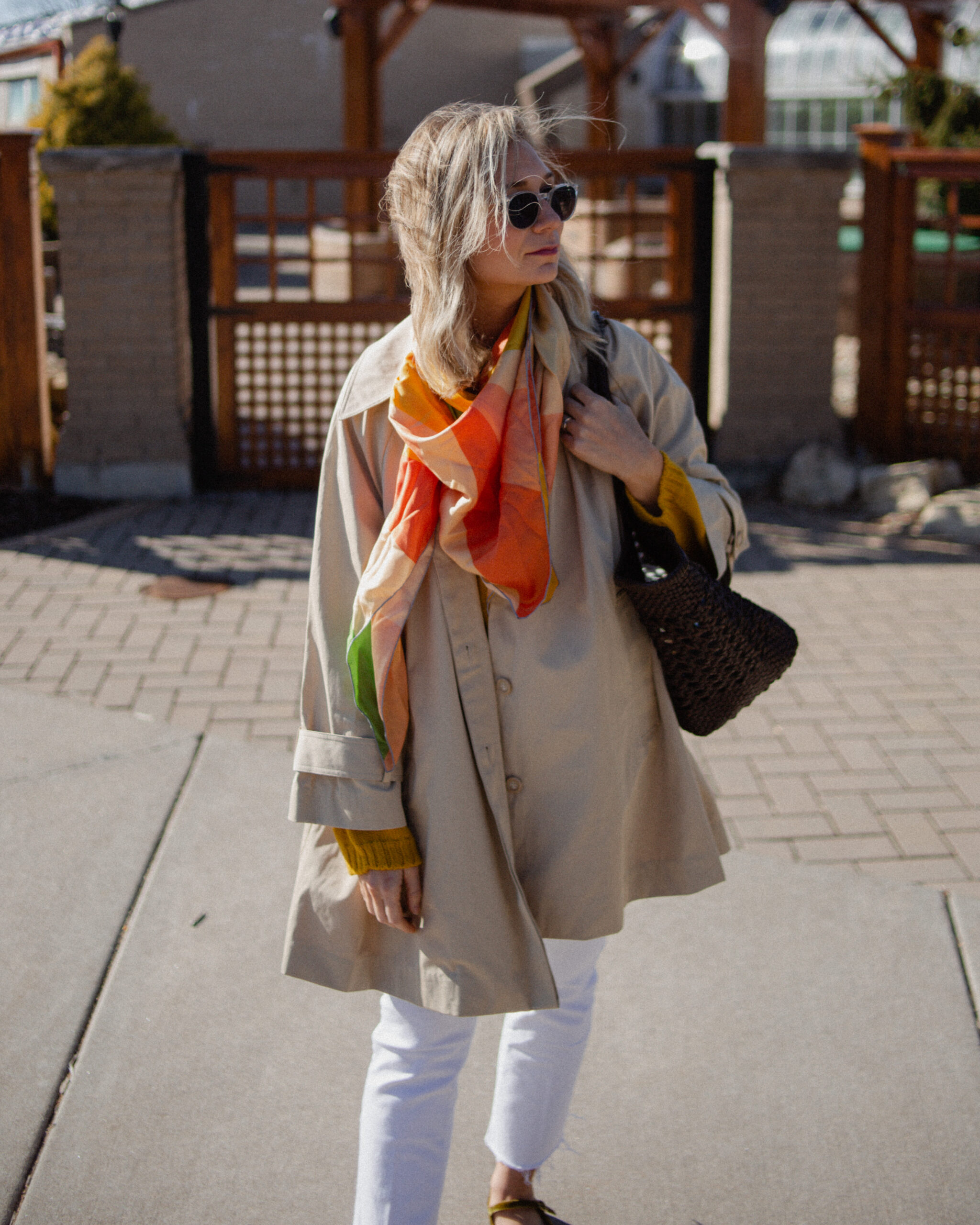 Karin Emily wears a A Classic Trench Coat with a Twist , white jeans, yellow sweater, colorful silk scarf, and green mary jane flats