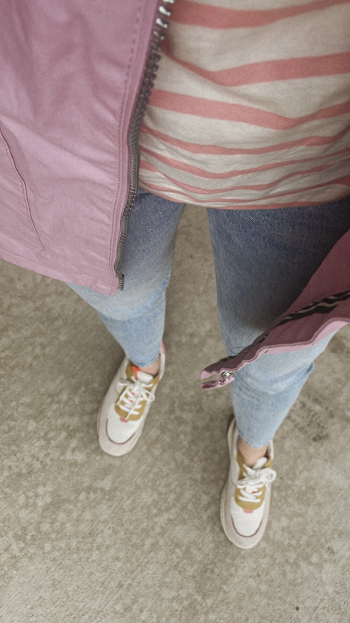 Karin Emily wears a pink breton stripe tee, pink raincoat, and rainbow sneakers with light wash levi jeans