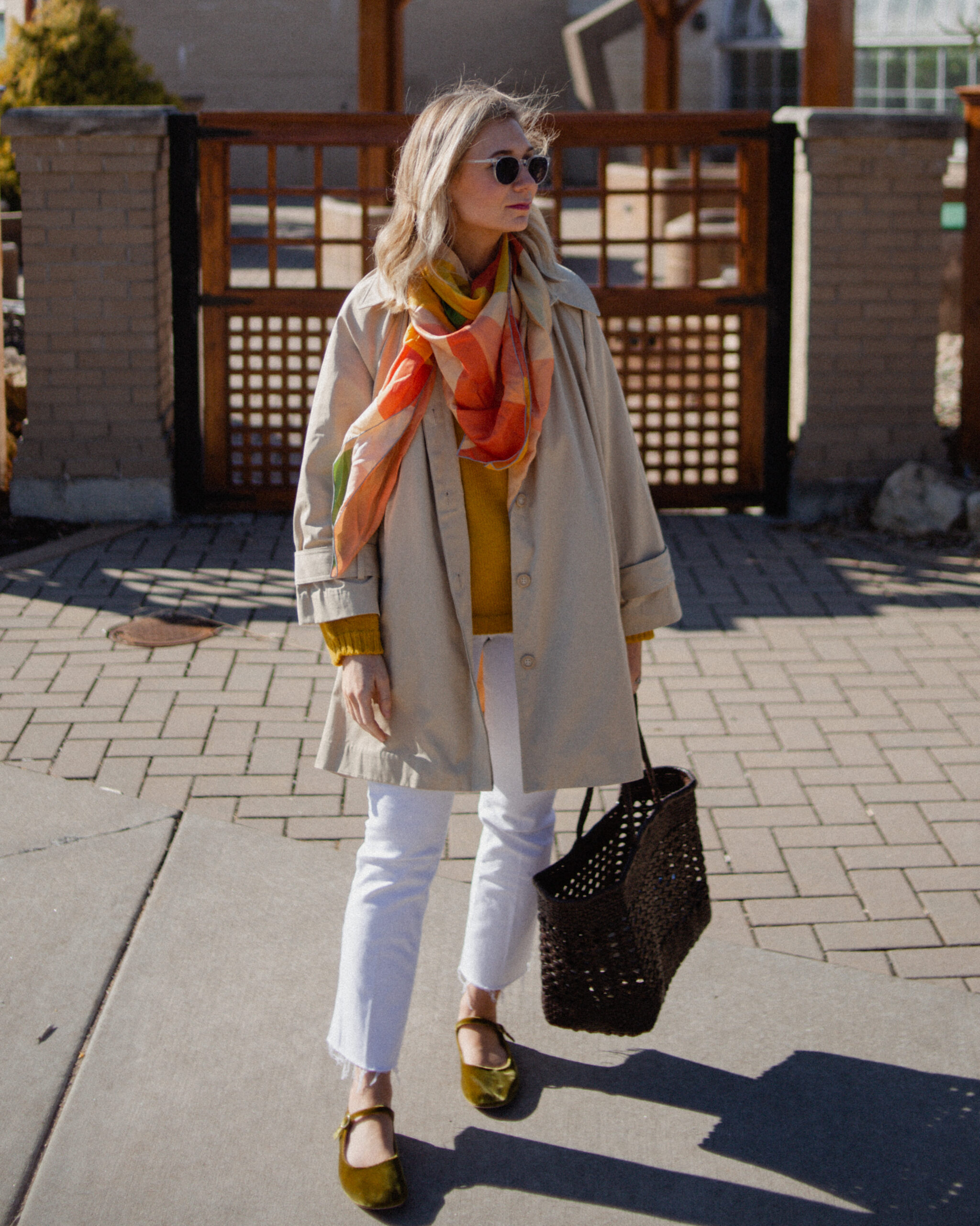 Karin Emily wears a A Classic Trench Coat with a Twist , white jeans, yellow sweater, colorful silk scarf, and green mary jane flats