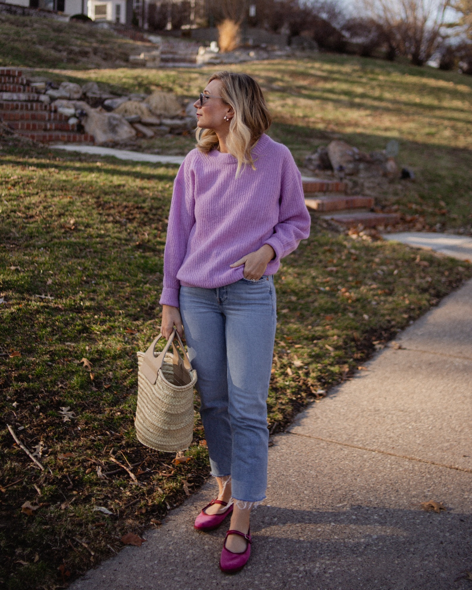 Karin Emily wears a purple sweater with light wash re/done jeans, and pink mary jane flats