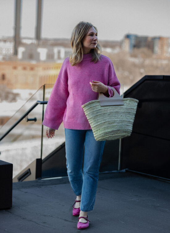 Karin Emily wears a pink sweater, blue jeans, and a pair of pink Mary Jane's