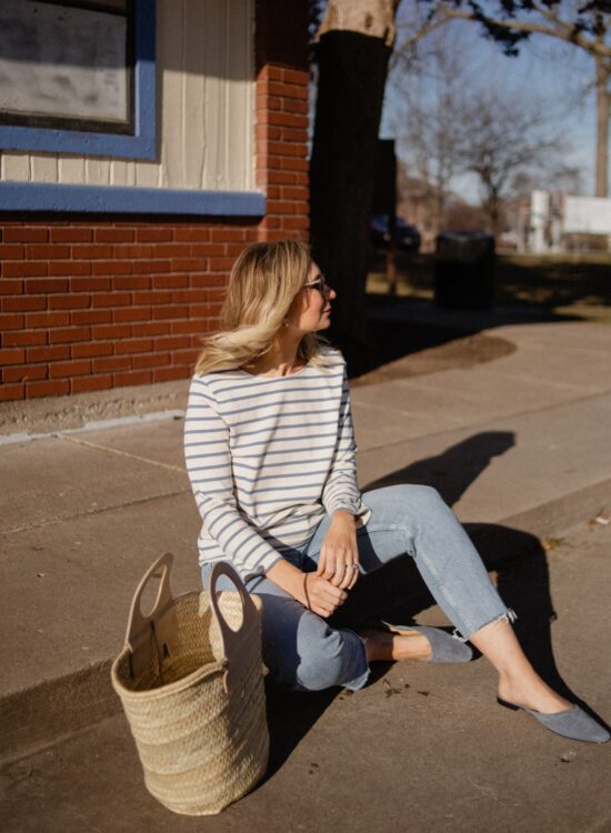 Karin Emily wears Breton stripes from Sezane with a pair of light wash stovepipe jeans from re/done and blue suede mules from Jack Erwin and a basket bag from Hereu