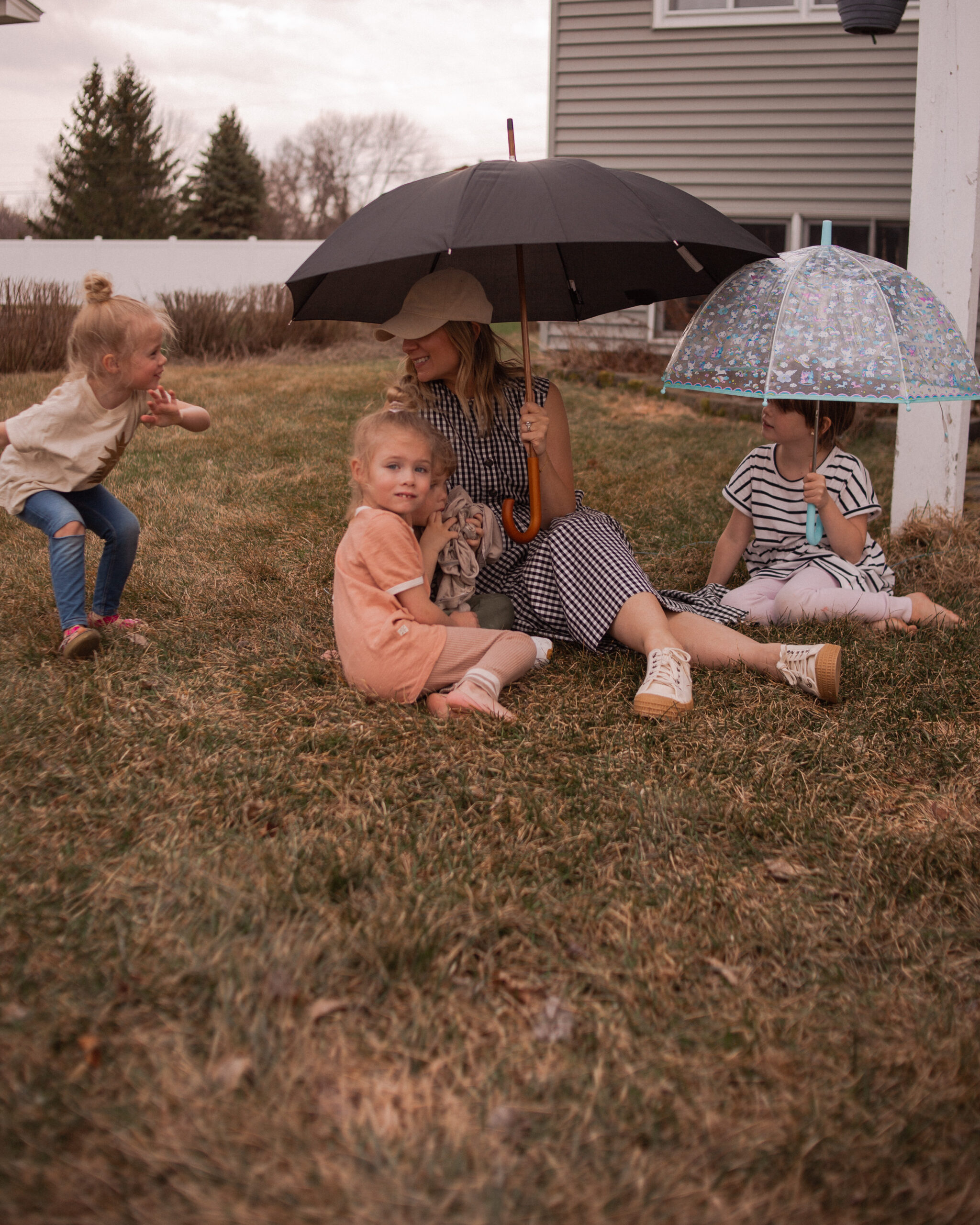 Karin Emily sits under an umbrella with her kids sitting around her