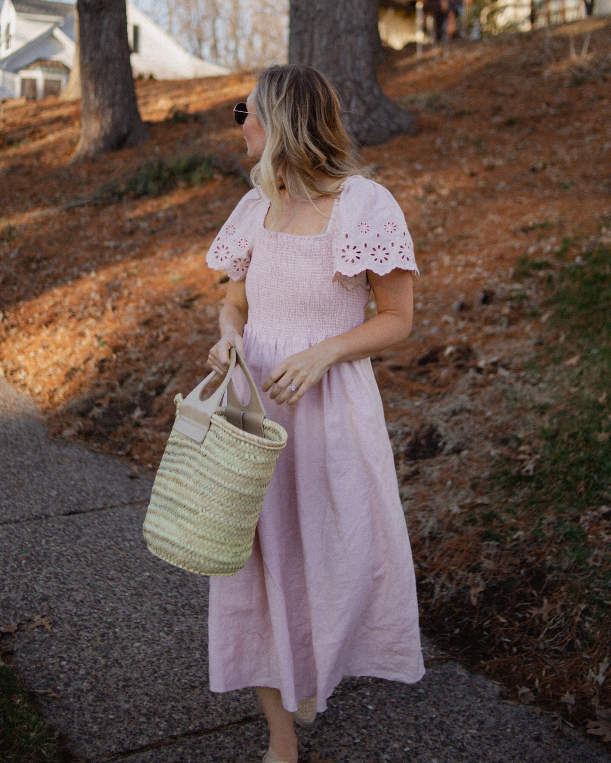 Karin Emily wears a pink dress with a smocked bodice, and lace sleeves from her Madewell Sale Edit