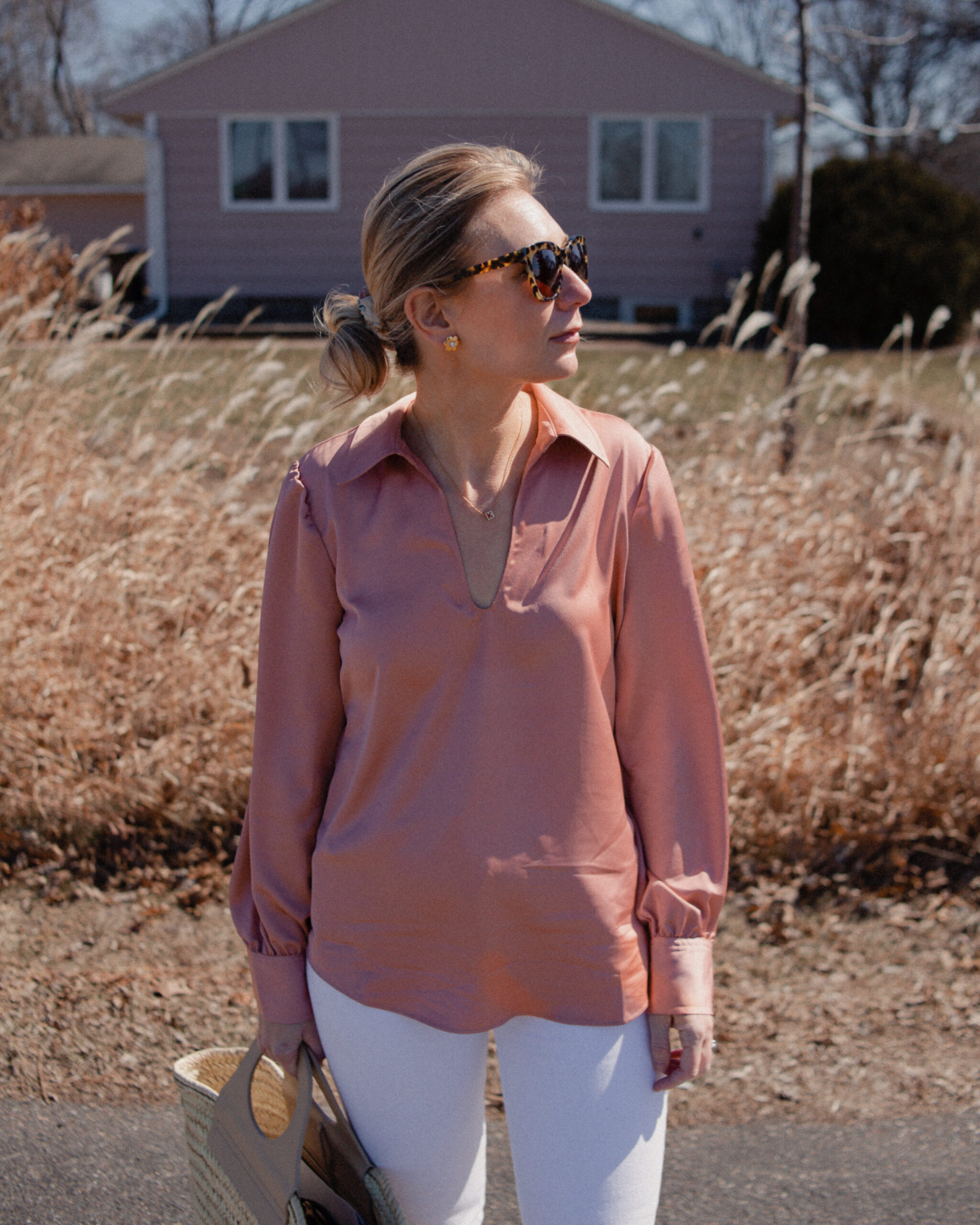 Karin Emily wears a pink satin blouse over white jeans