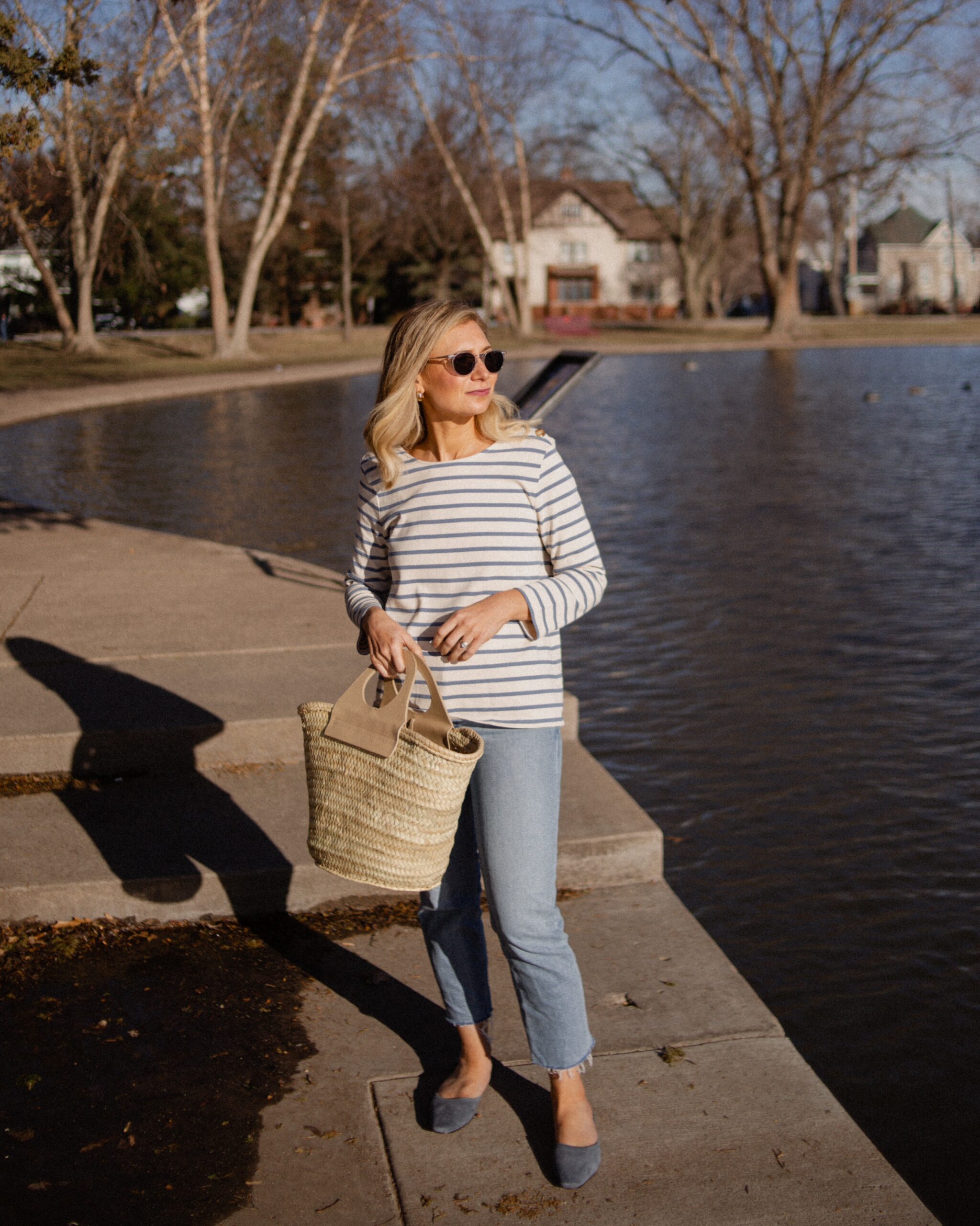 Karin Emily wears Breton stripes from Sezane with a pair of light wash stovepipe jeans from re/done and blue suede mules from Jack Erwin and a basket bag from Hereu
