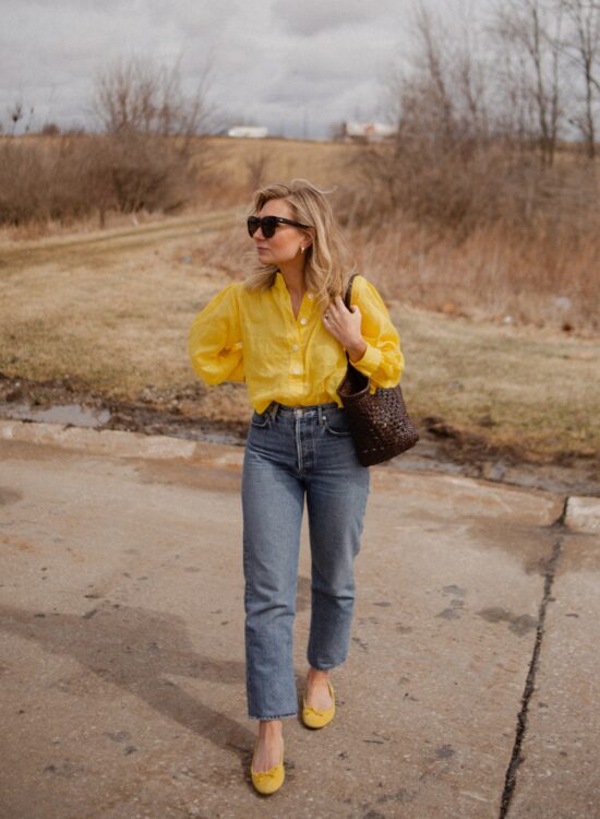 Karin Emily wears a bright yellow spring blouses, straight leg jeans from agolde, yellow ballet flats and a bag from dragon diffusion