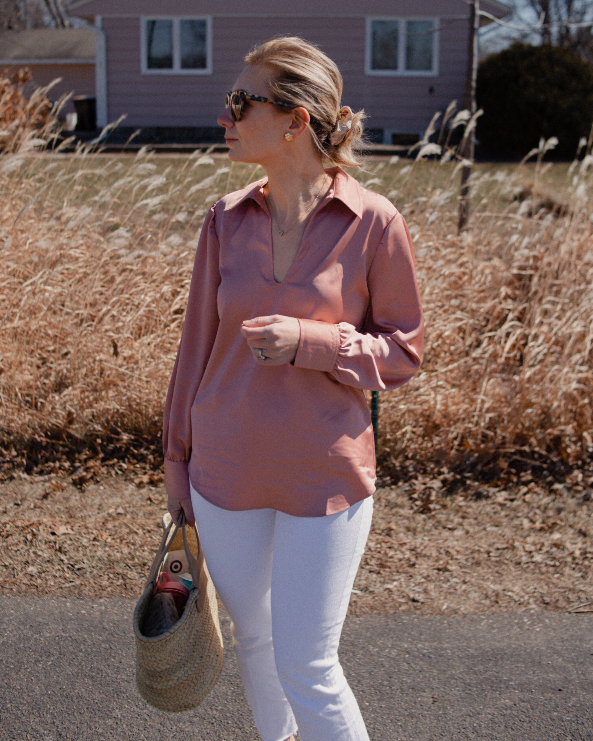 Karin Emily wears a pink satin blouse over white jeans paired with nude mary jane flats and a hereu basket bag