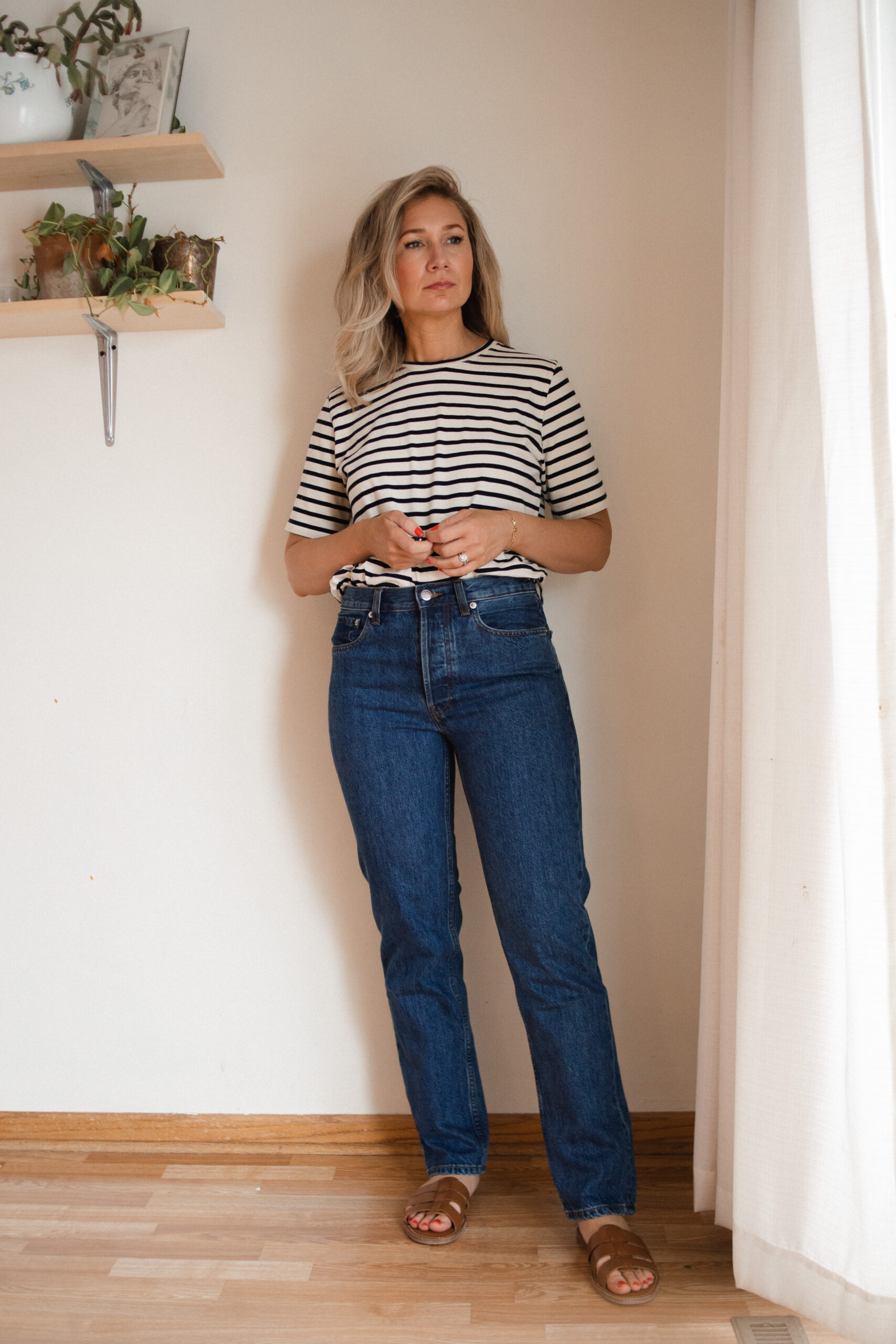 Karin Emily wears the Everlane everyone vintage jeansa, a pair of brown sandals nd a black and white tee