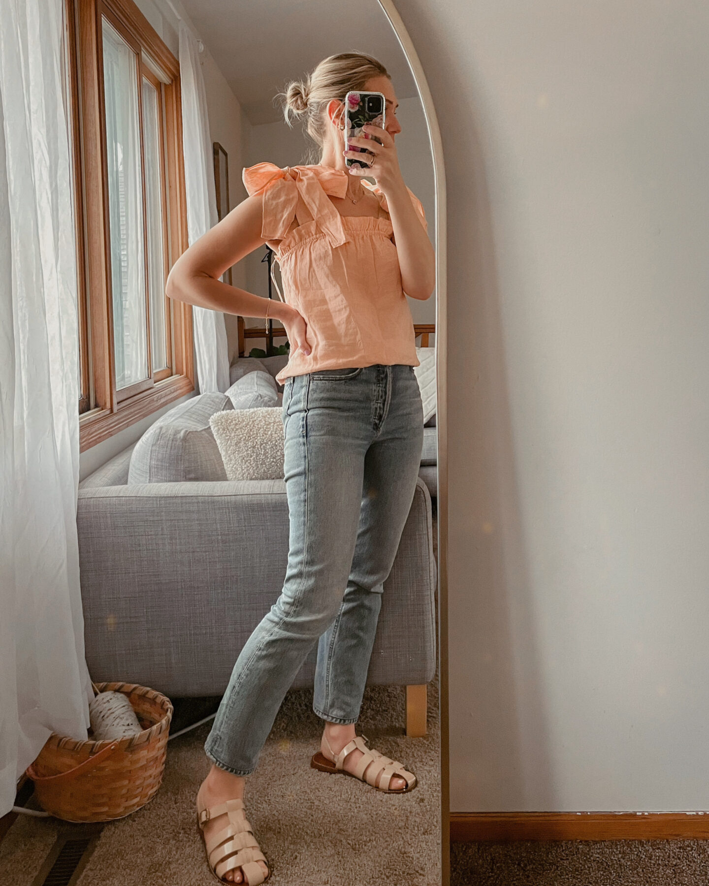Karin Emily wears a linen coral tank top for spring with light wash jeans and fisherman sandals