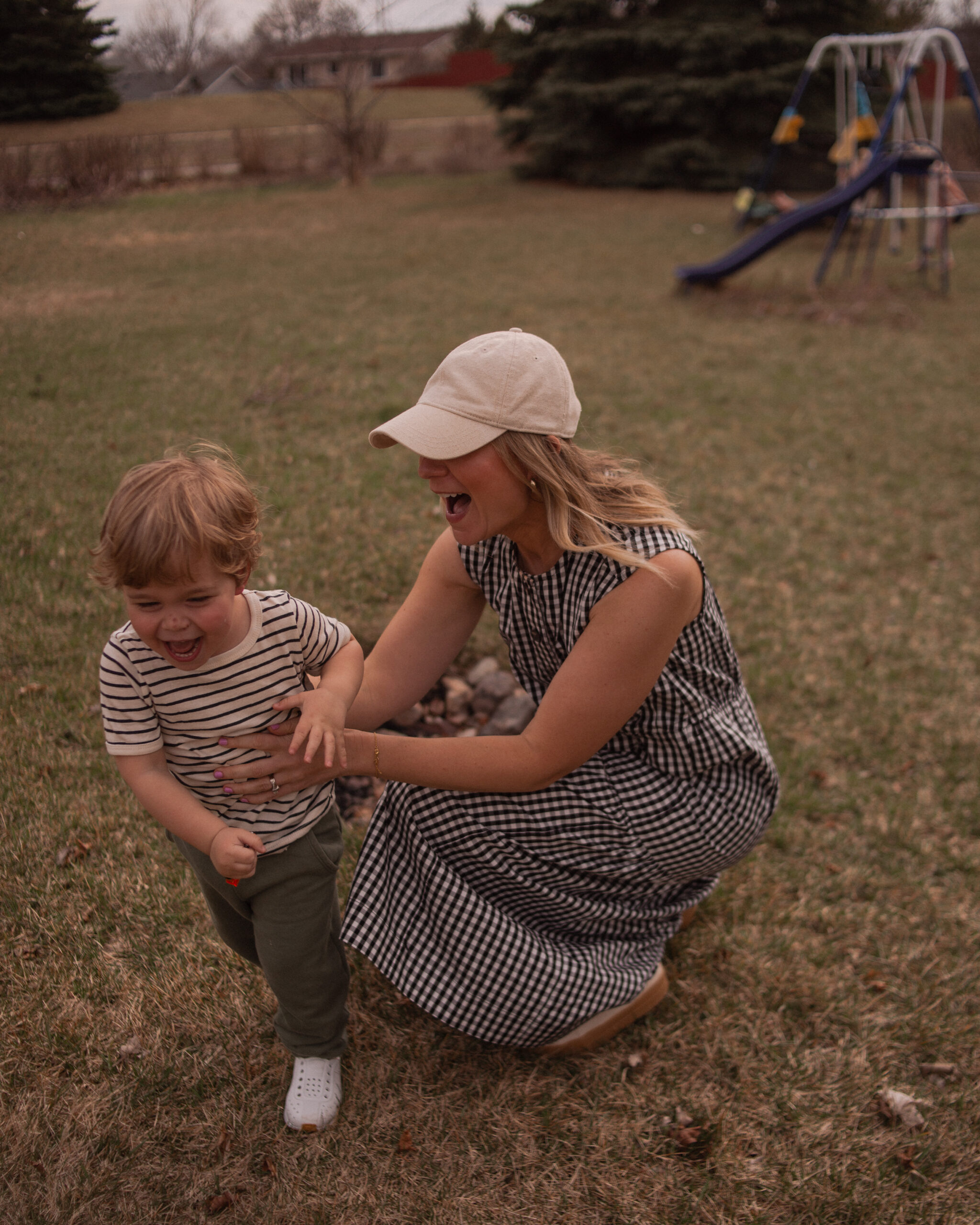 Karin Emily wears a gingham maxi dress from Everlane with canvas sneakers and a neutral baseball hat