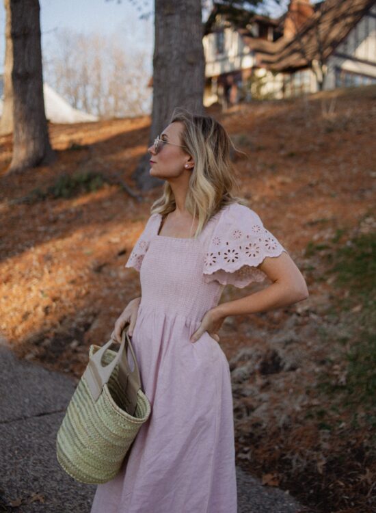 Karin Emily wears a pink dress with a smocked bodice, and lace sleeves from her Madewell Sale Edit