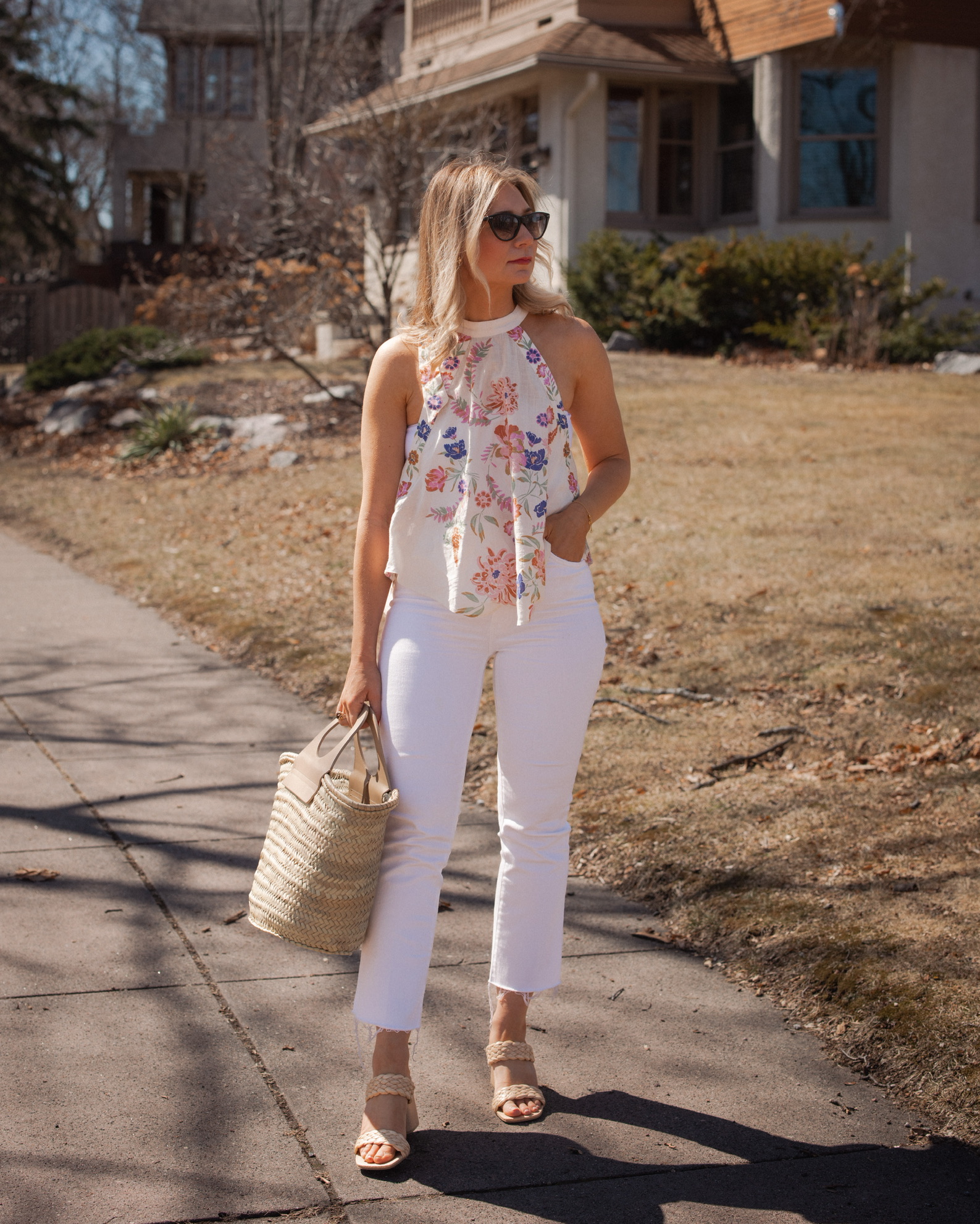 Karin Emily shares a mother's day brunch look with a floral halter top, white crop top, white jeans from Mother, raffia heeled sandals, Isabel Marant Sunglasses, and a bag from Hereu