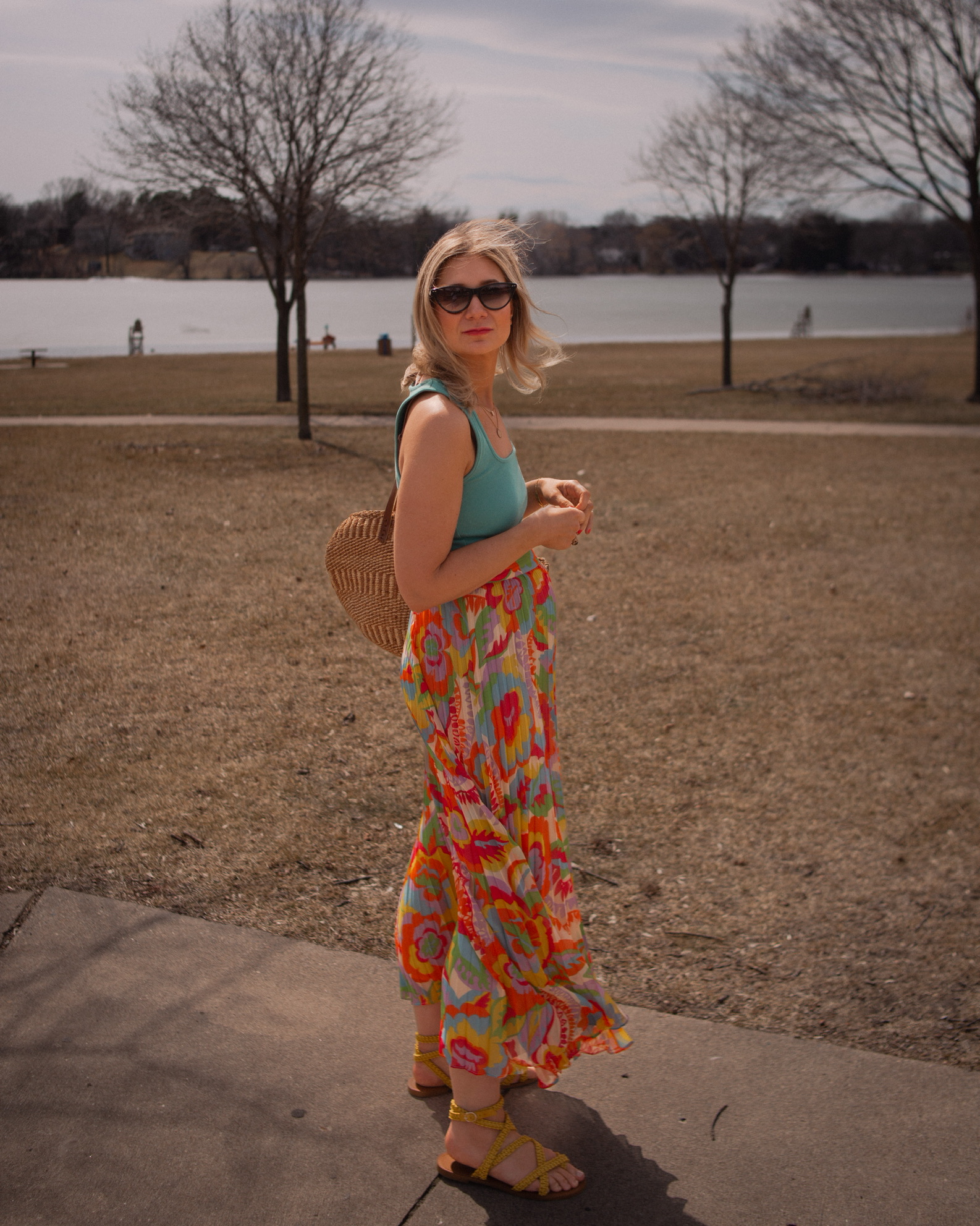 Karin Emily wears a turquoise juan t-shirt from Sezane with A brightly colored floral maxi skirt, yellow sandals, and Isabel Marant Cat Eye Sunglasses