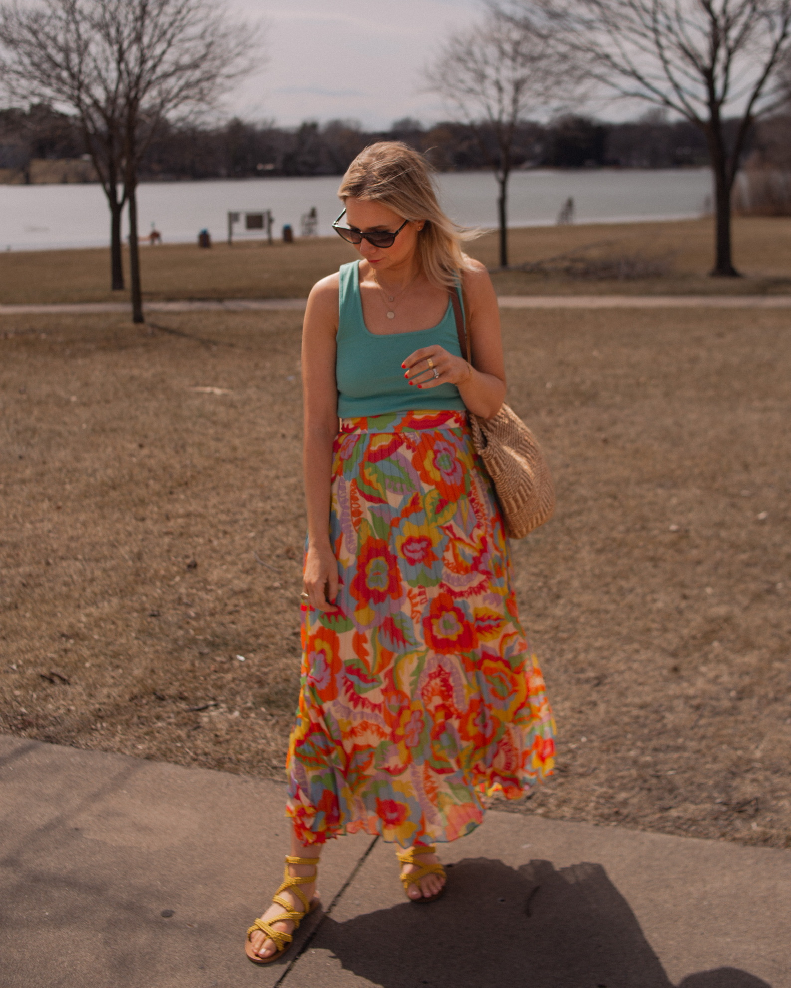 Karin Emily wears a turquoise juan t-shirt from Sezane with A brightly colored floral maxi skirt, yellow sandals, and Isabel Marant Cat Eye Sunglasses